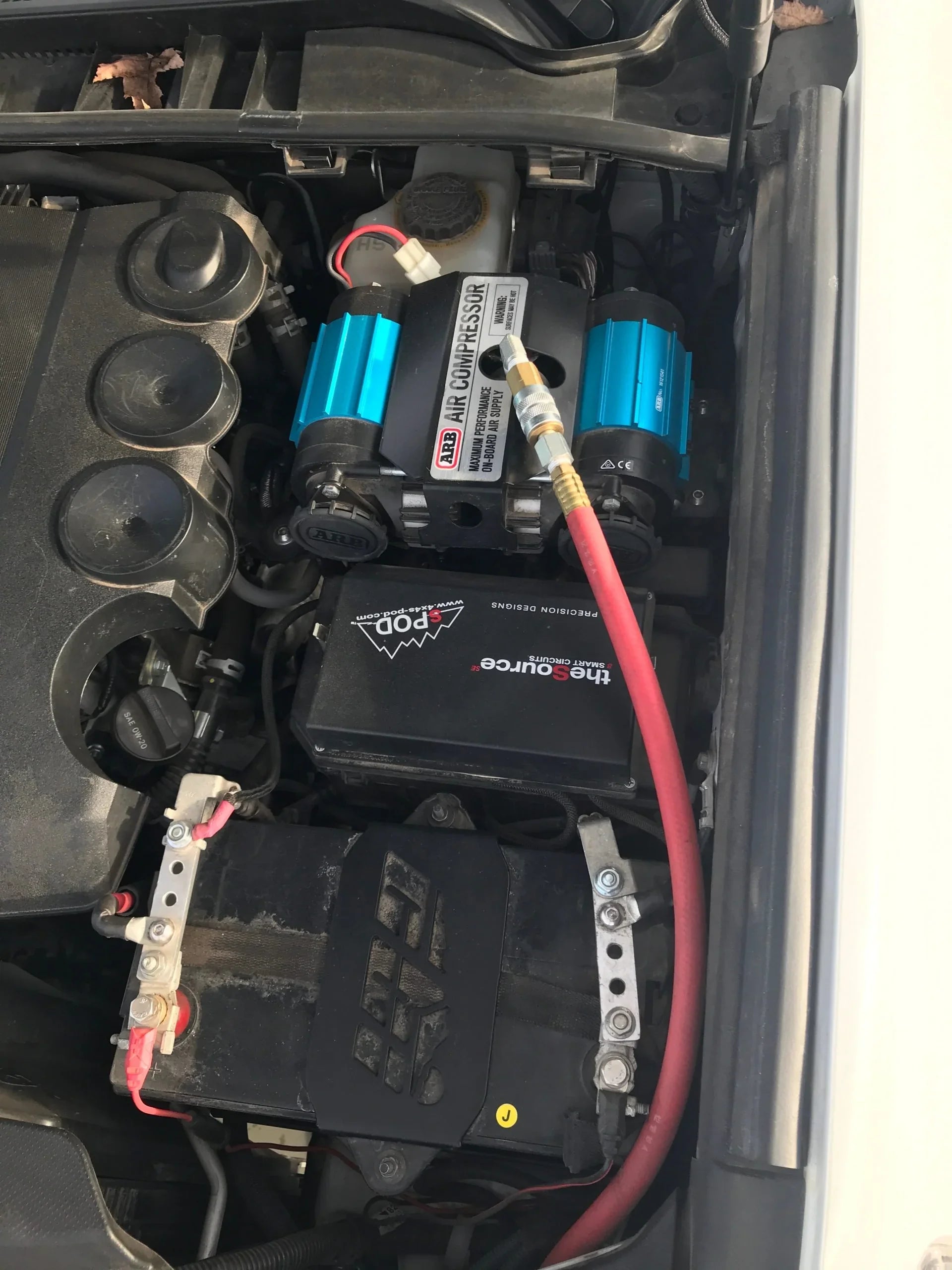 ARB dual air compressor installed in vehicle engine bay with battery and smart circuit for overlanding