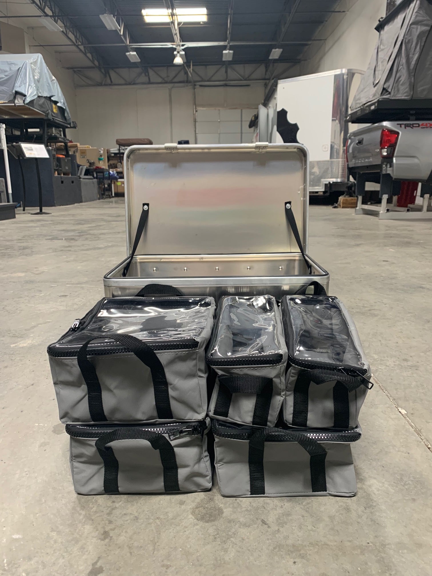 Overlanding gear storage case with six gray organizer bags in a garage setting