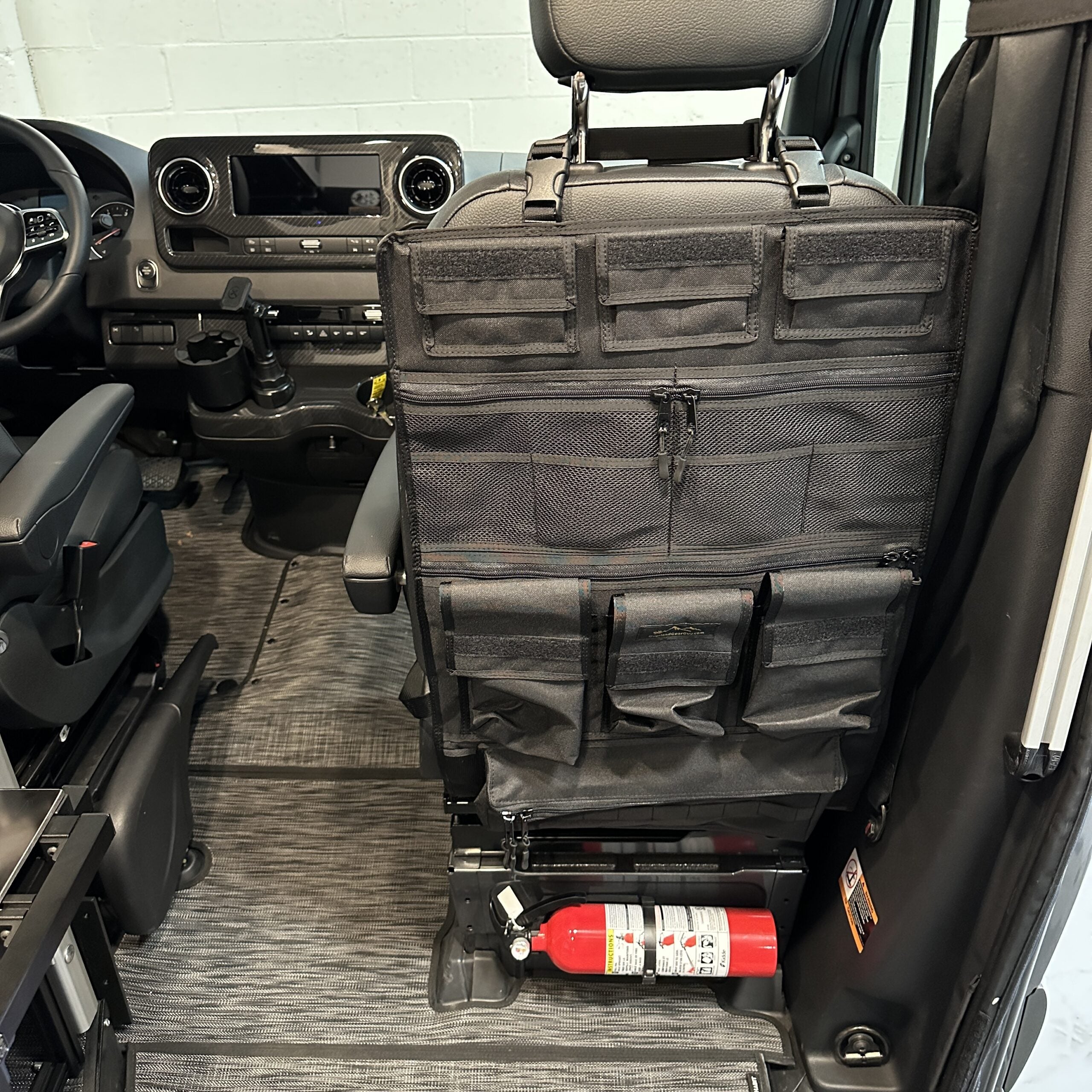 Vehicle seat back organizer with storage pouches and fire extinguisher in adventure van