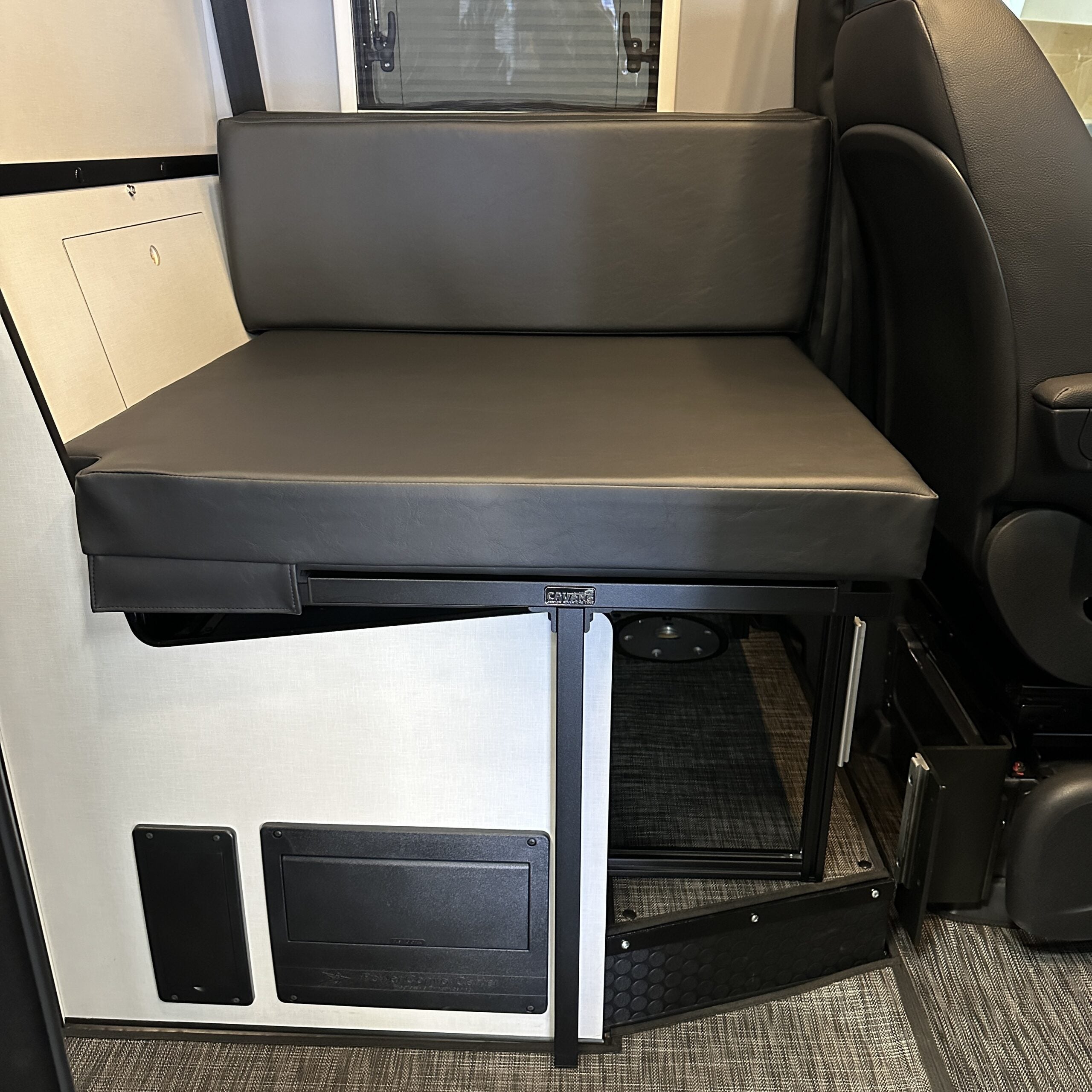 Camper van interior bench seat with black cushion and under-seat storage