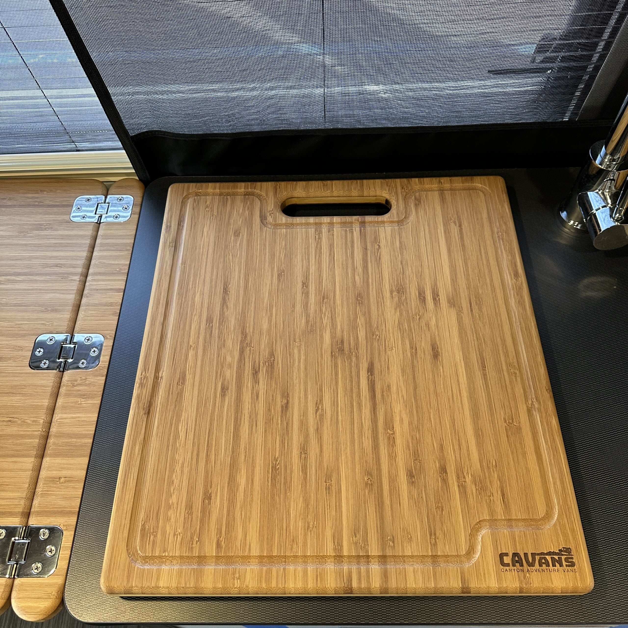 Bamboo cutting board with handle slot in overland camping vehicle kitchenette