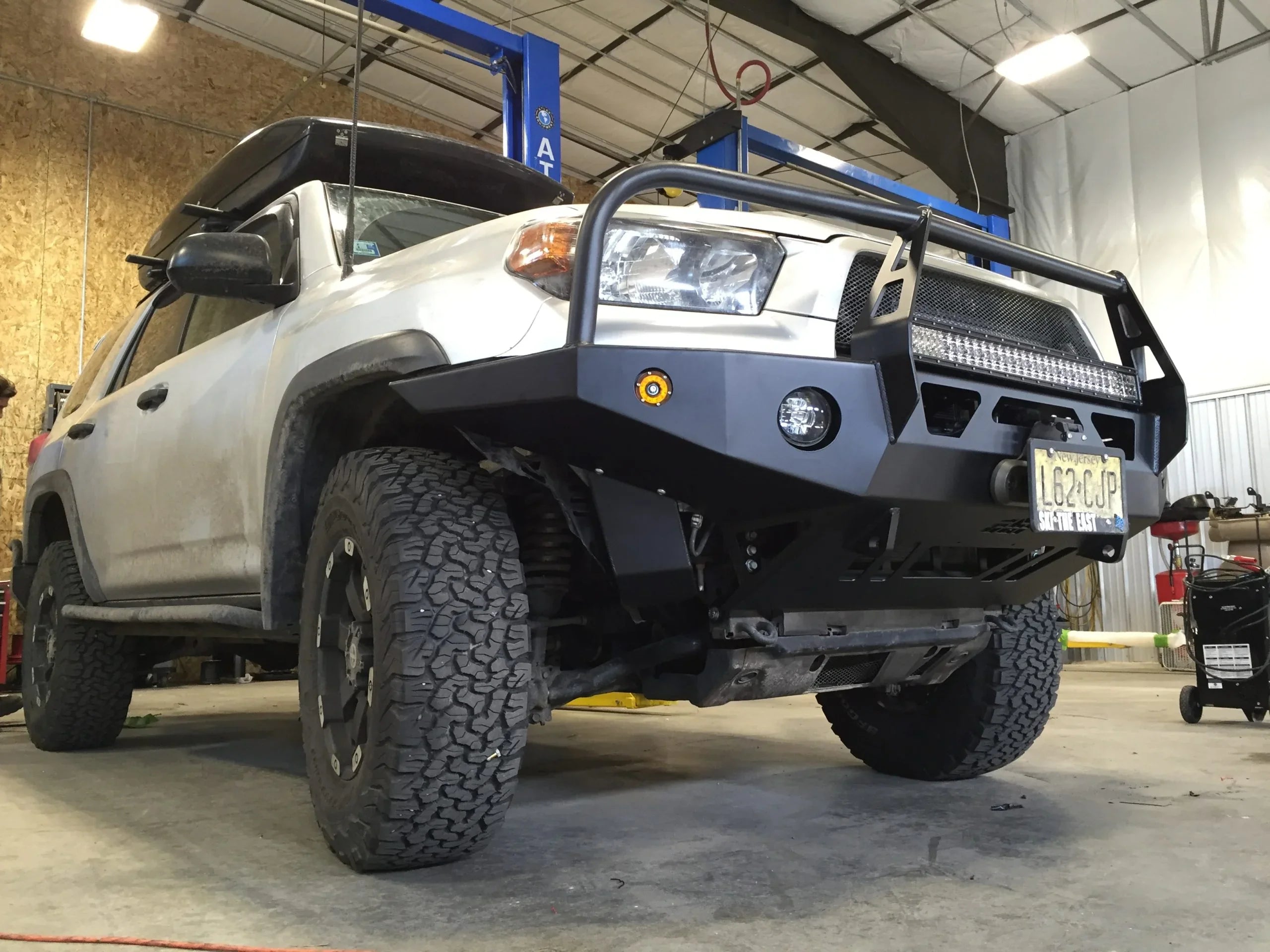 Lifted Toyota 4Runner with off-road front bumper, roof cargo box, and all-terrain tires in a garage