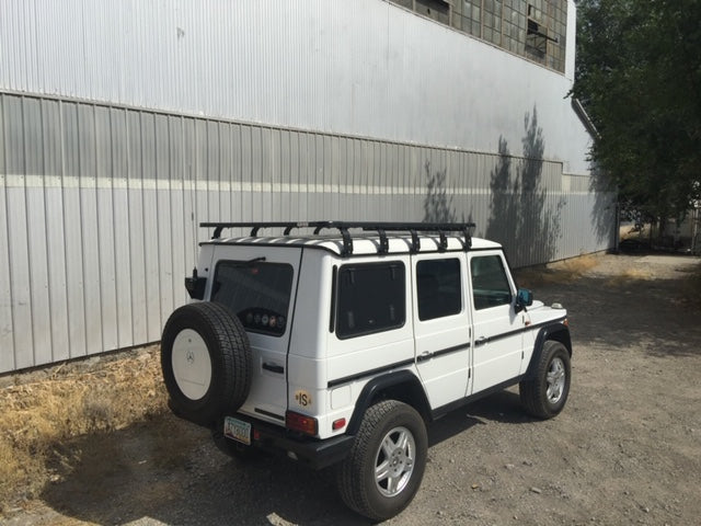 White off-road SUV with roof rack parked outdoors, ready for overlanding adventure gear