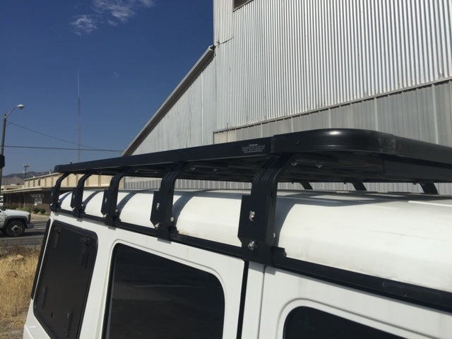 Heavy-duty roof rack installed on white off-road vehicle beside industrial building