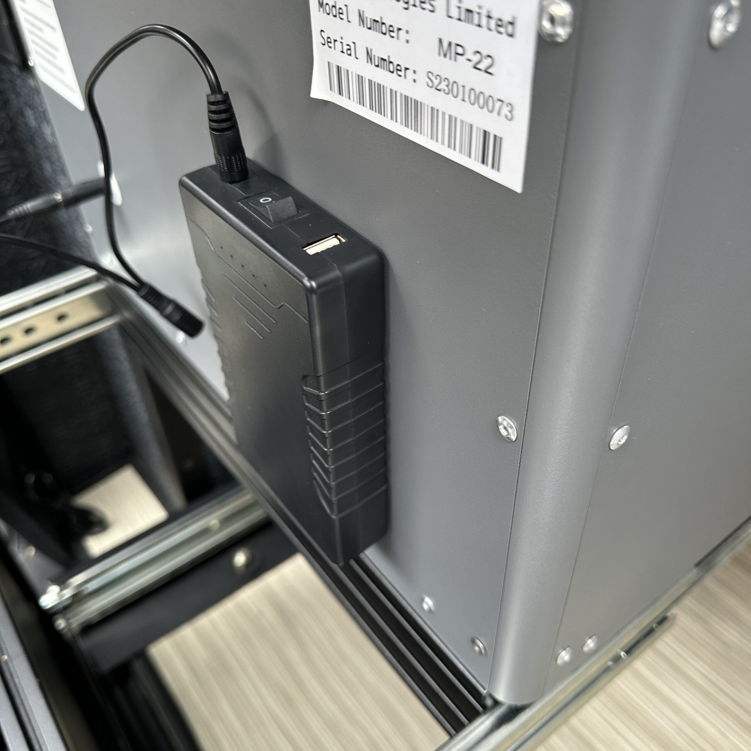 Close-up of power control switch and cable on rugged metal device in overland vehicle drawer