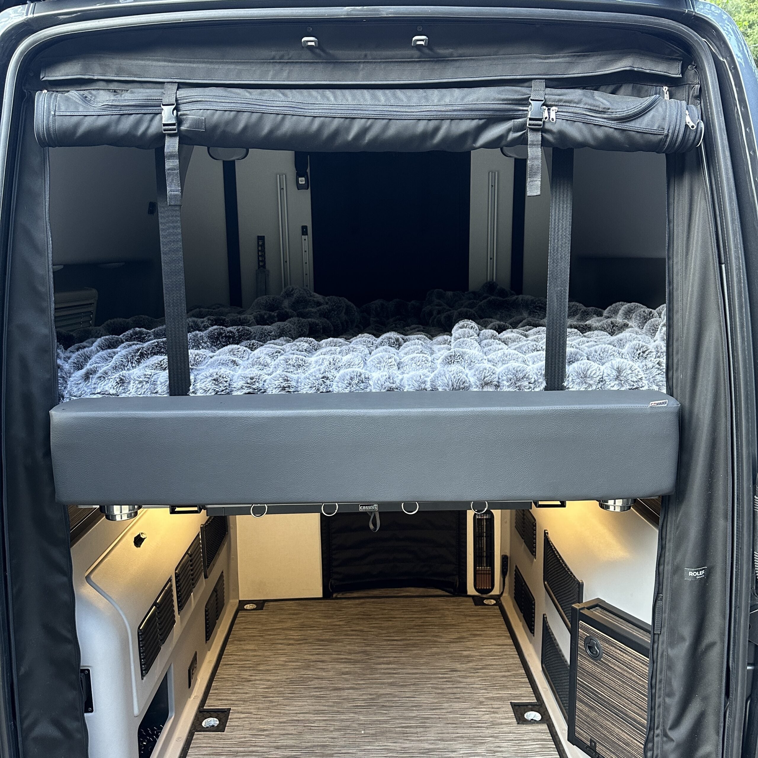 Overlanding van rear interior with raised bed and storage area, ideal for expedition camping.