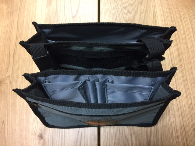 Top view of a gray overlanding gear organizer pouch with multiple compartments on a wood table