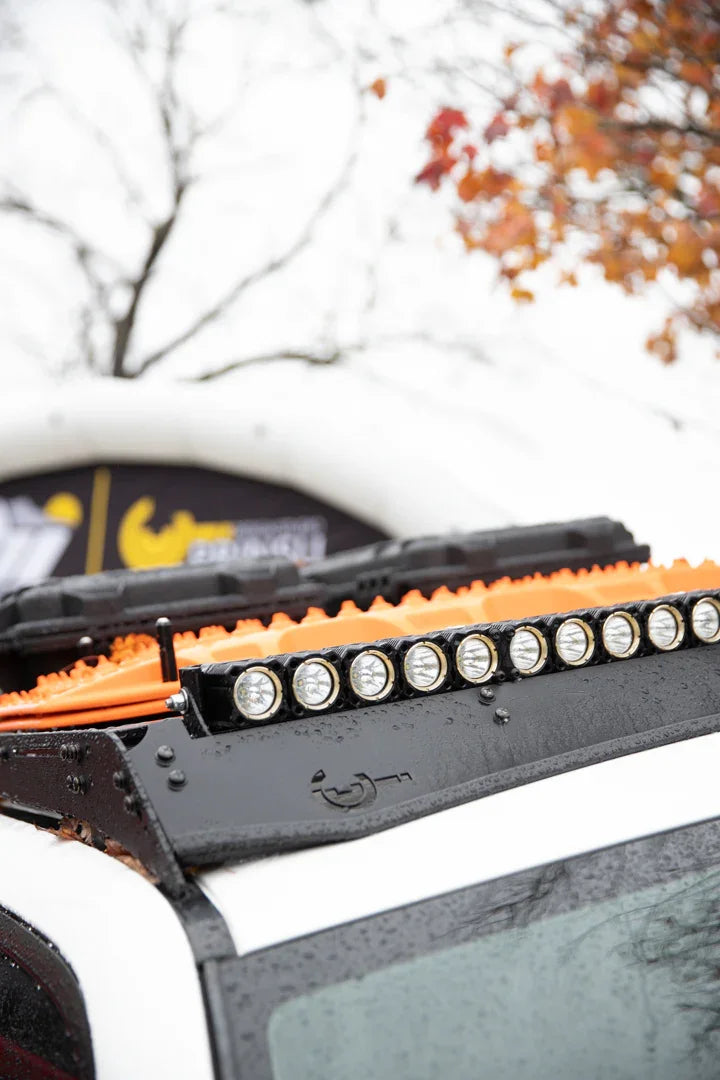 LED light bar and orange recovery boards mounted on an off-road vehicle roof rack
