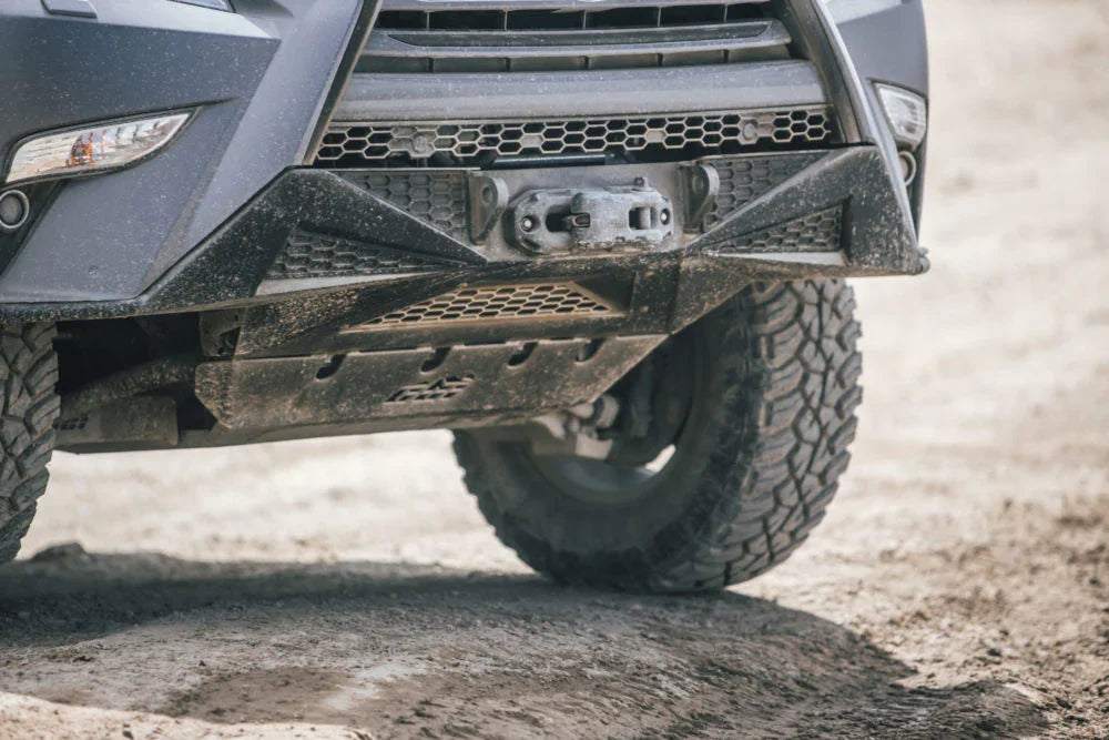 Off-road vehicle front bumper and skid plate with all-terrain tires on dirt trail