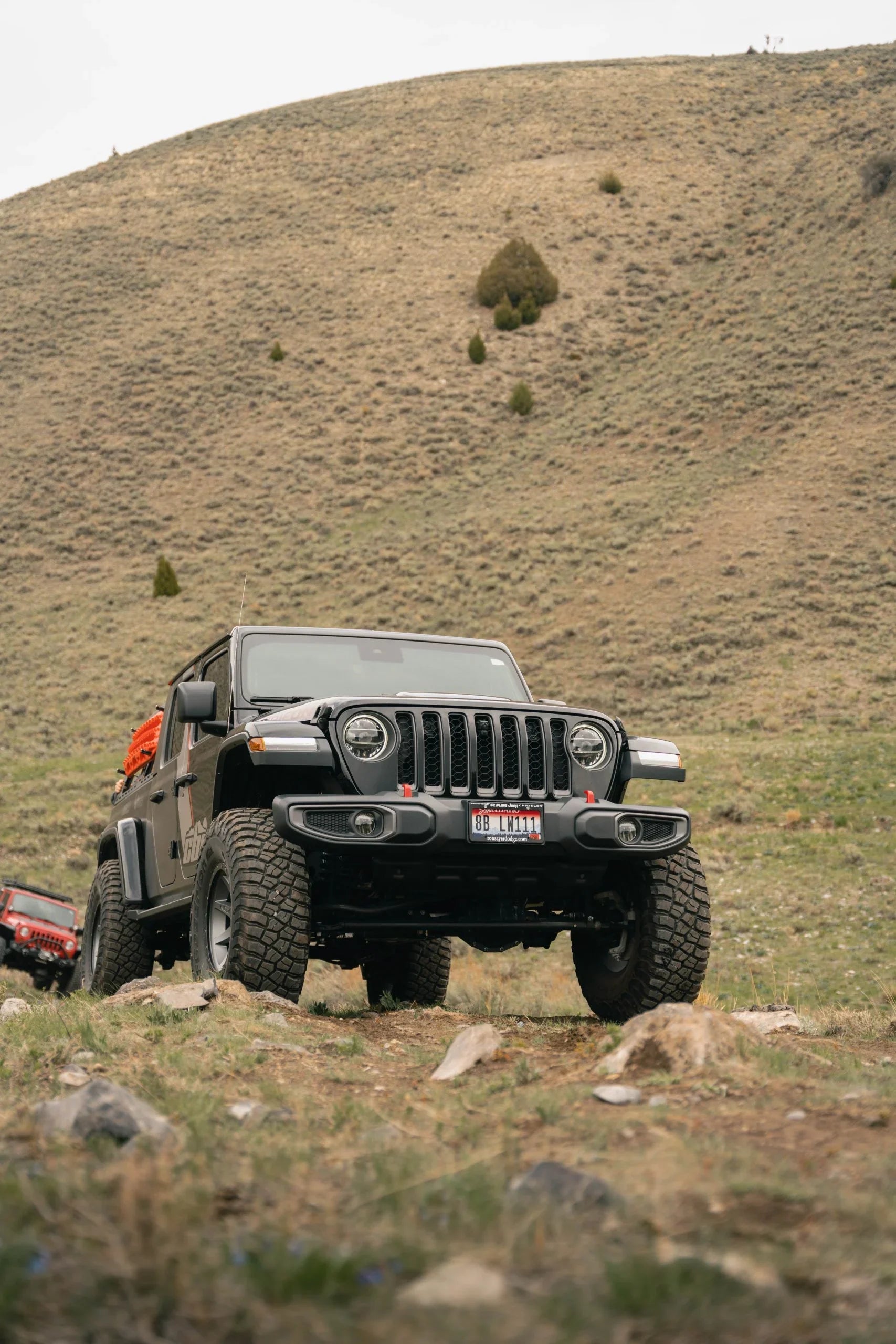 Jeep Gladiator with rock sliders off-roading on rocky terrain in a mountain landscape