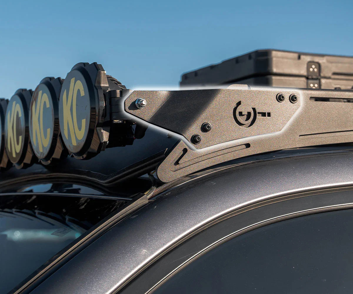 Overland vehicle roof rack bracket with mounted KC lights and gear case