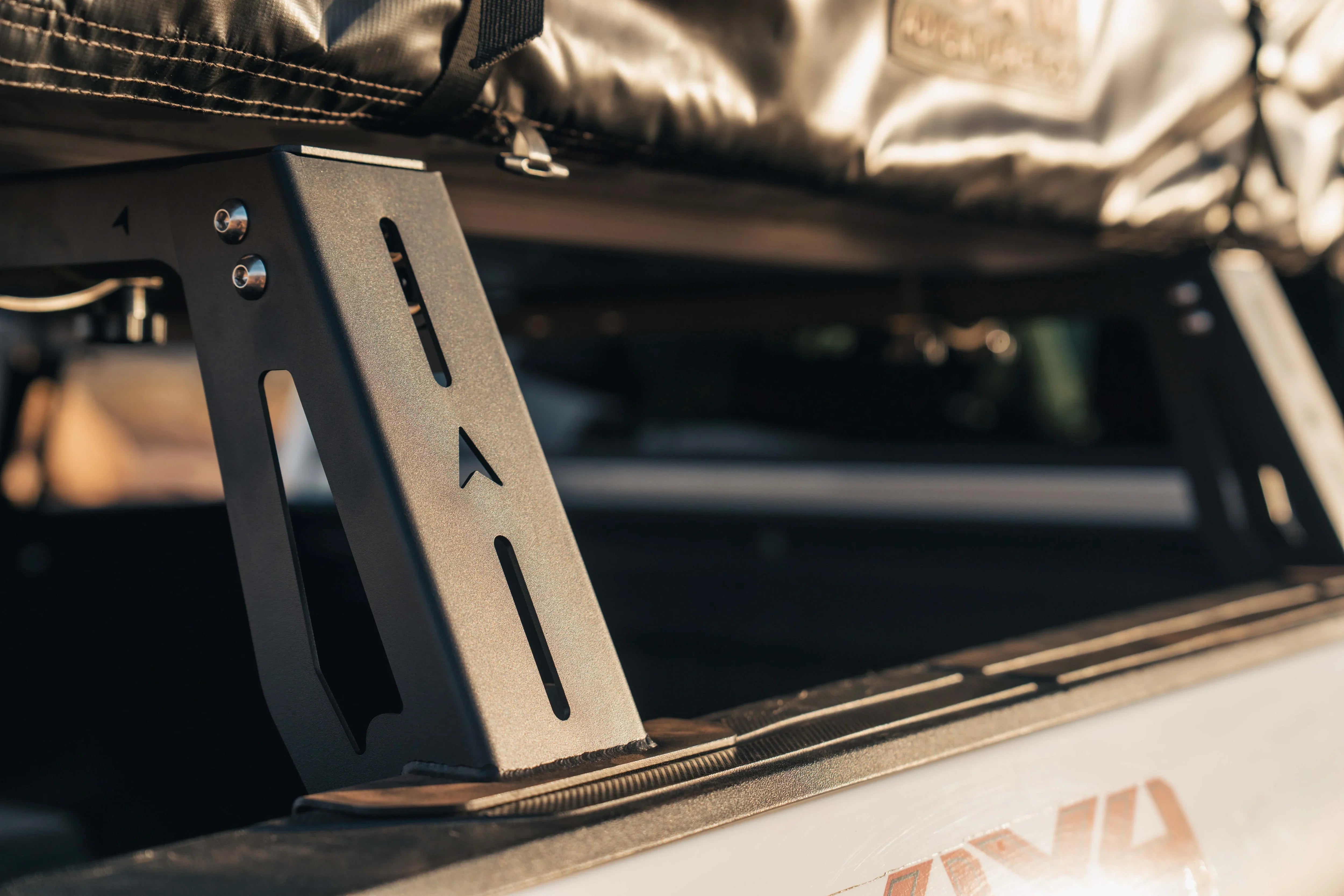 Close-up of a black metal truck bed rack mount for overlanding gear, sunlight detail