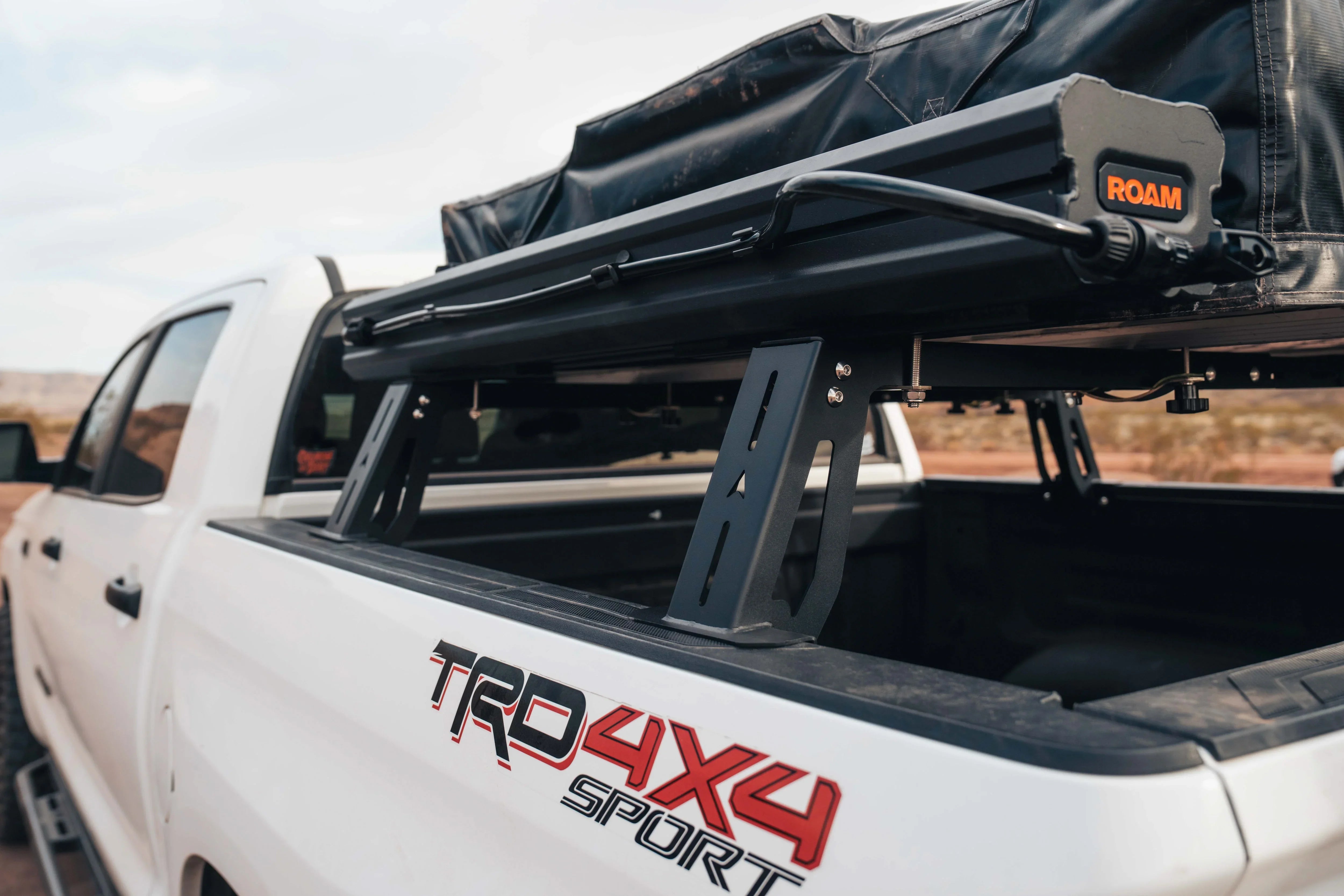 Toyota Tacoma TRD 4x4 Sport with overland bed rack and ROAM rooftop tent outdoors