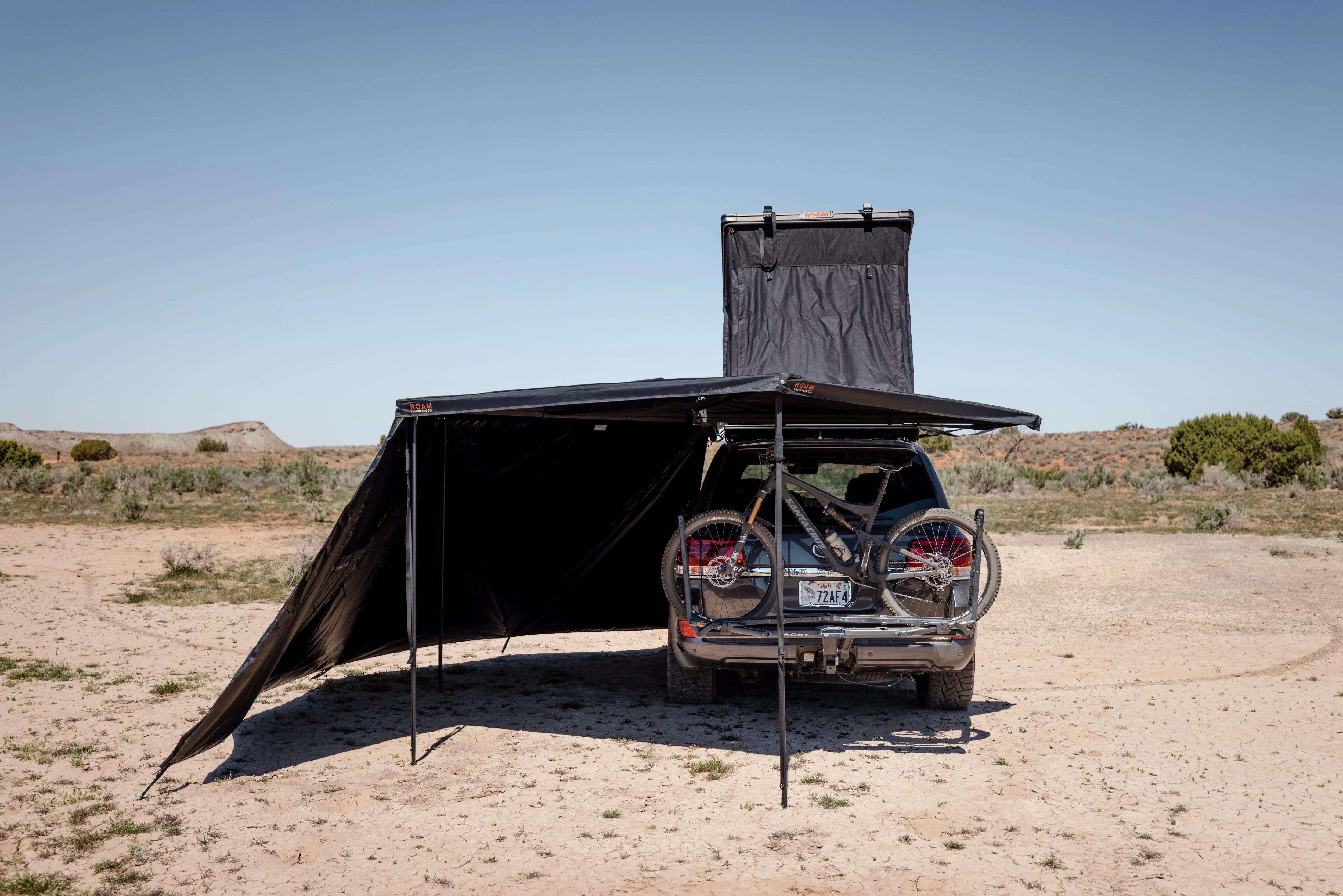 SUV with roof top tent, side awning, mountain bikes, overland camping in desert
