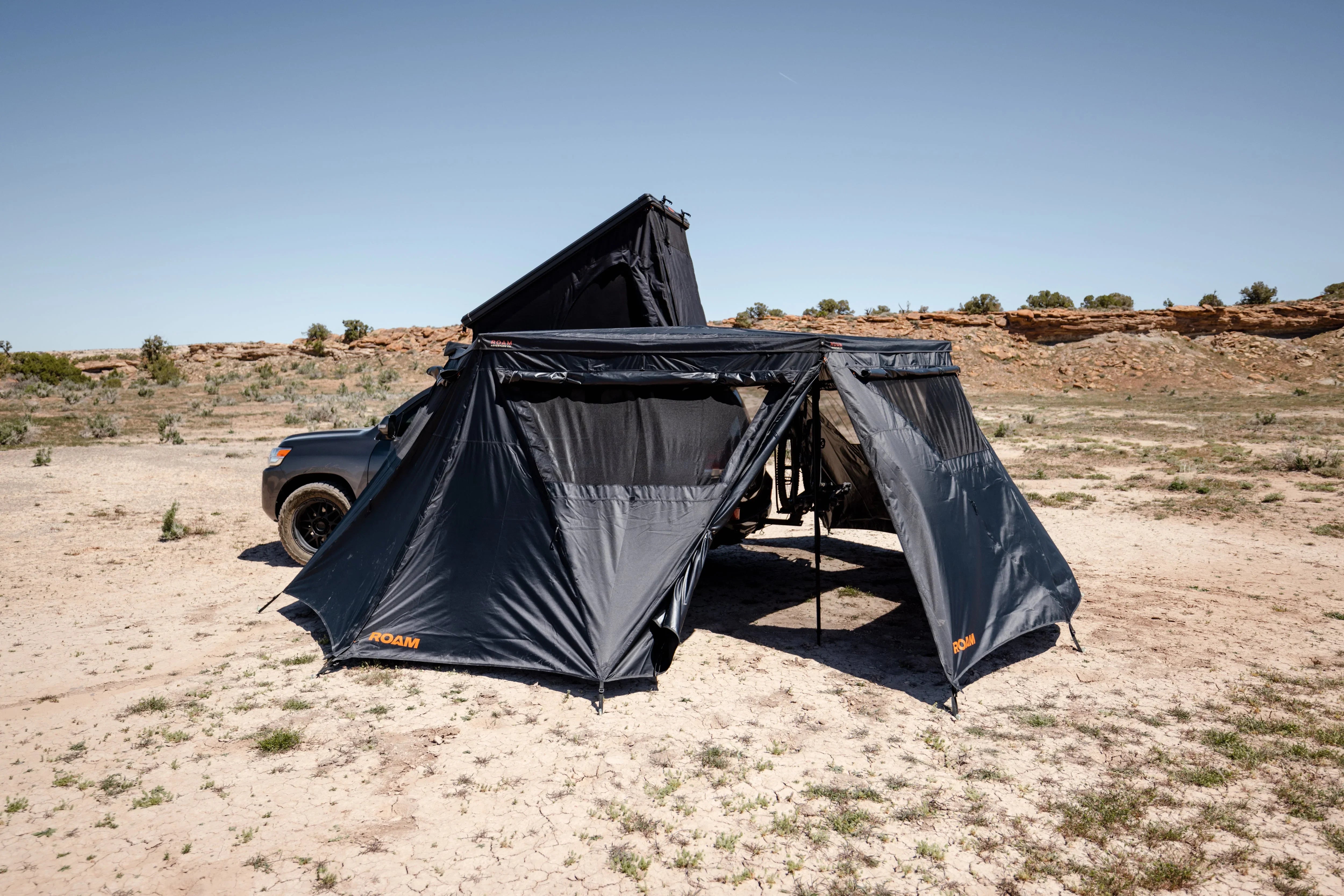Overland vehicle with rooftop tent and awning set up in desert landscape for camping