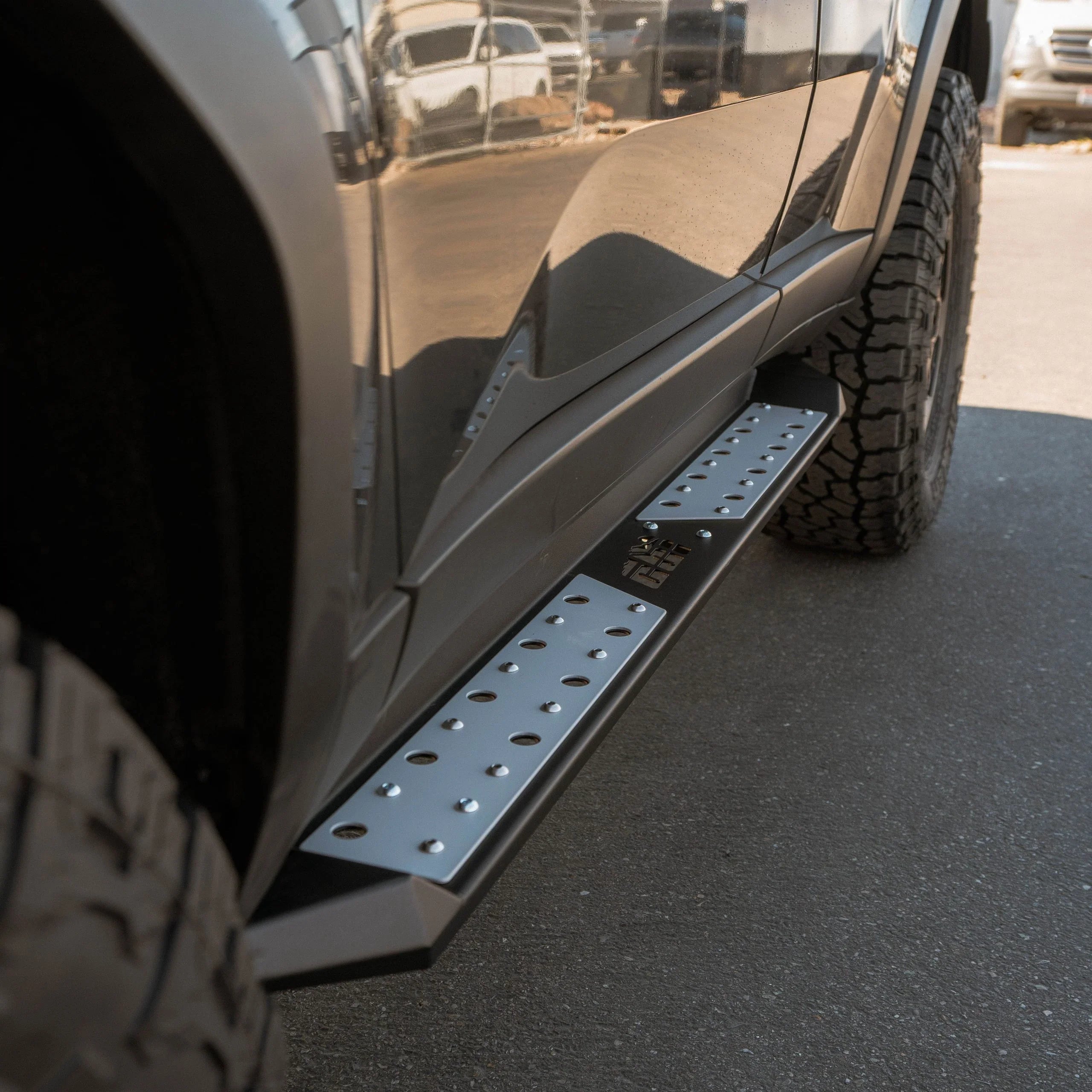 Close-up of off-road truck side step with textured metal surface and all-terrain tire