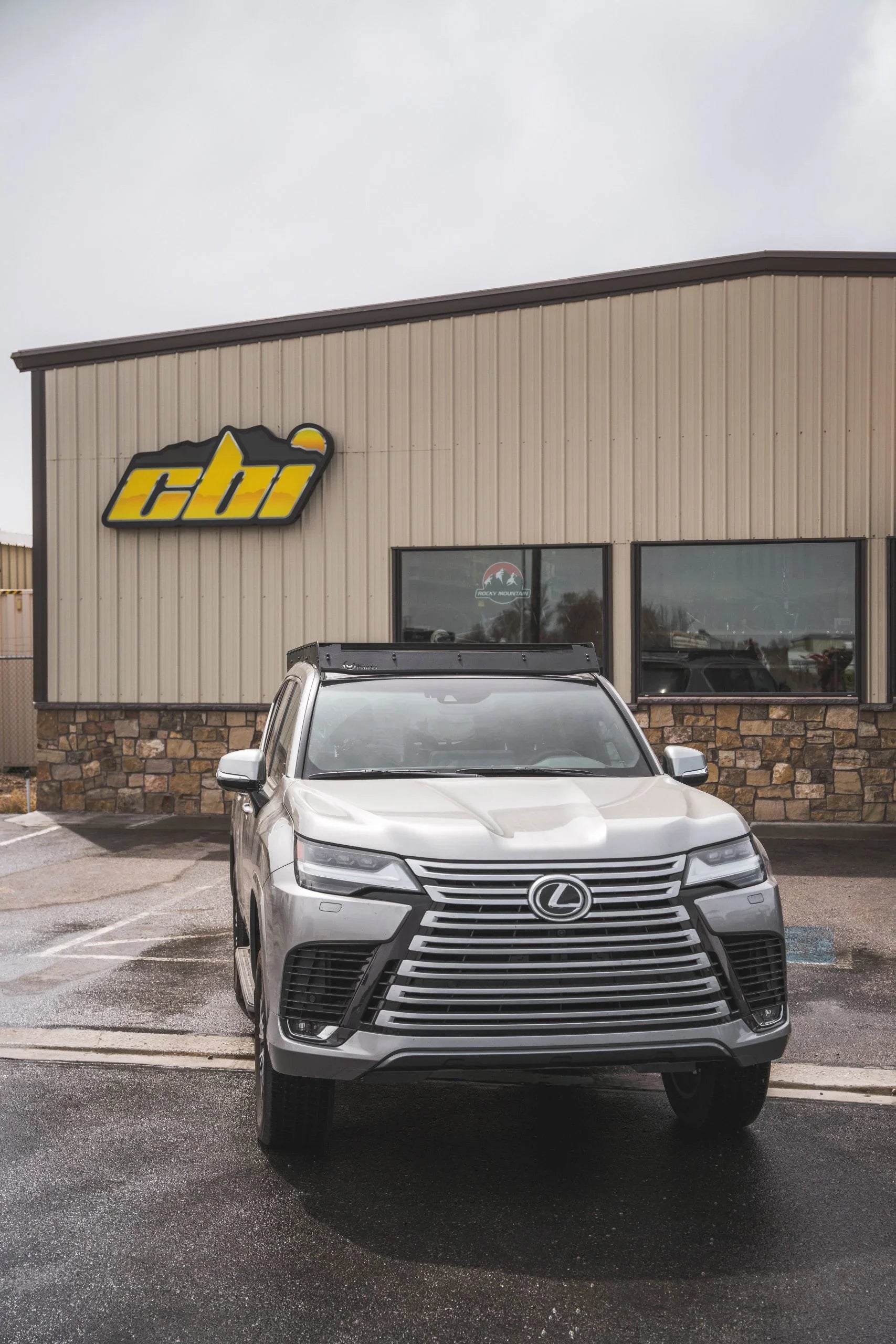 Lexus LX600 SUV with roof rack parked outside adventure gear store
