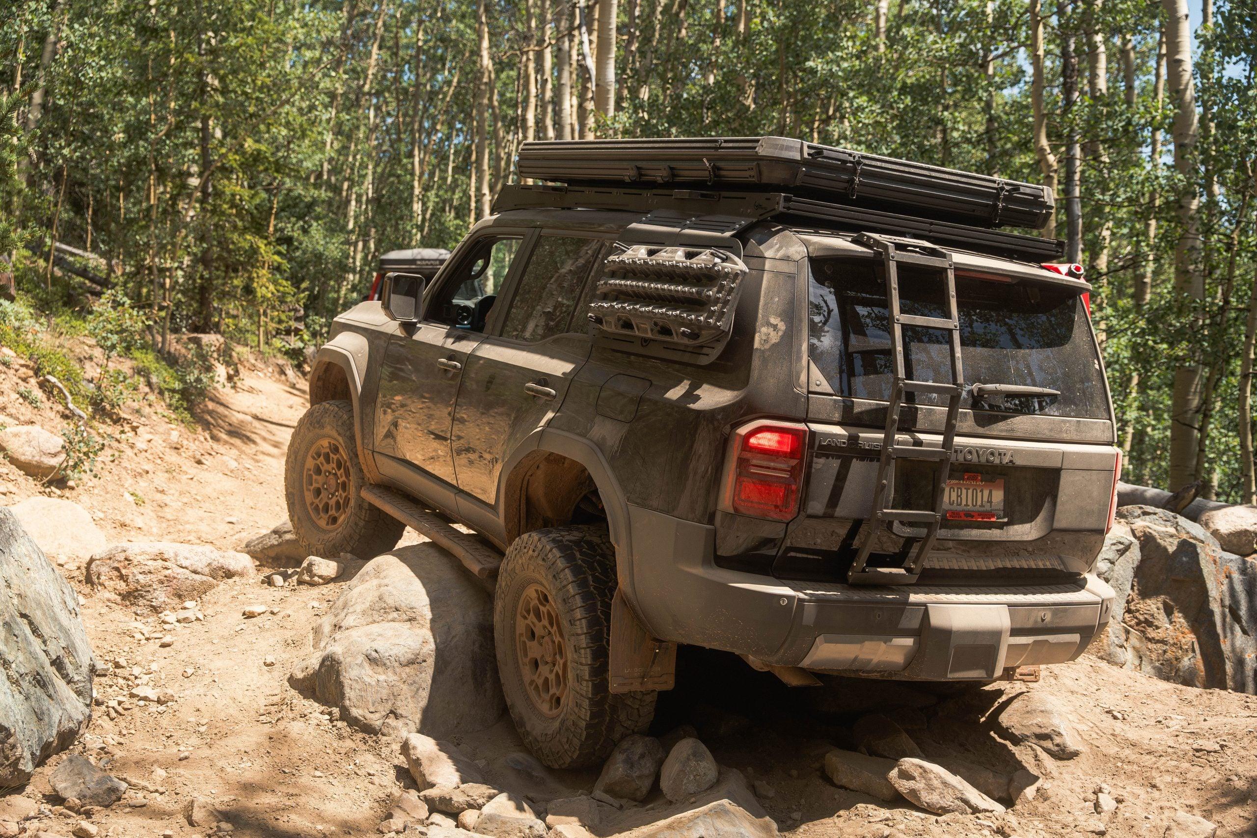 Toyota Land Cruiser off-roading on rocky trail with overlanding gear and rock sliders