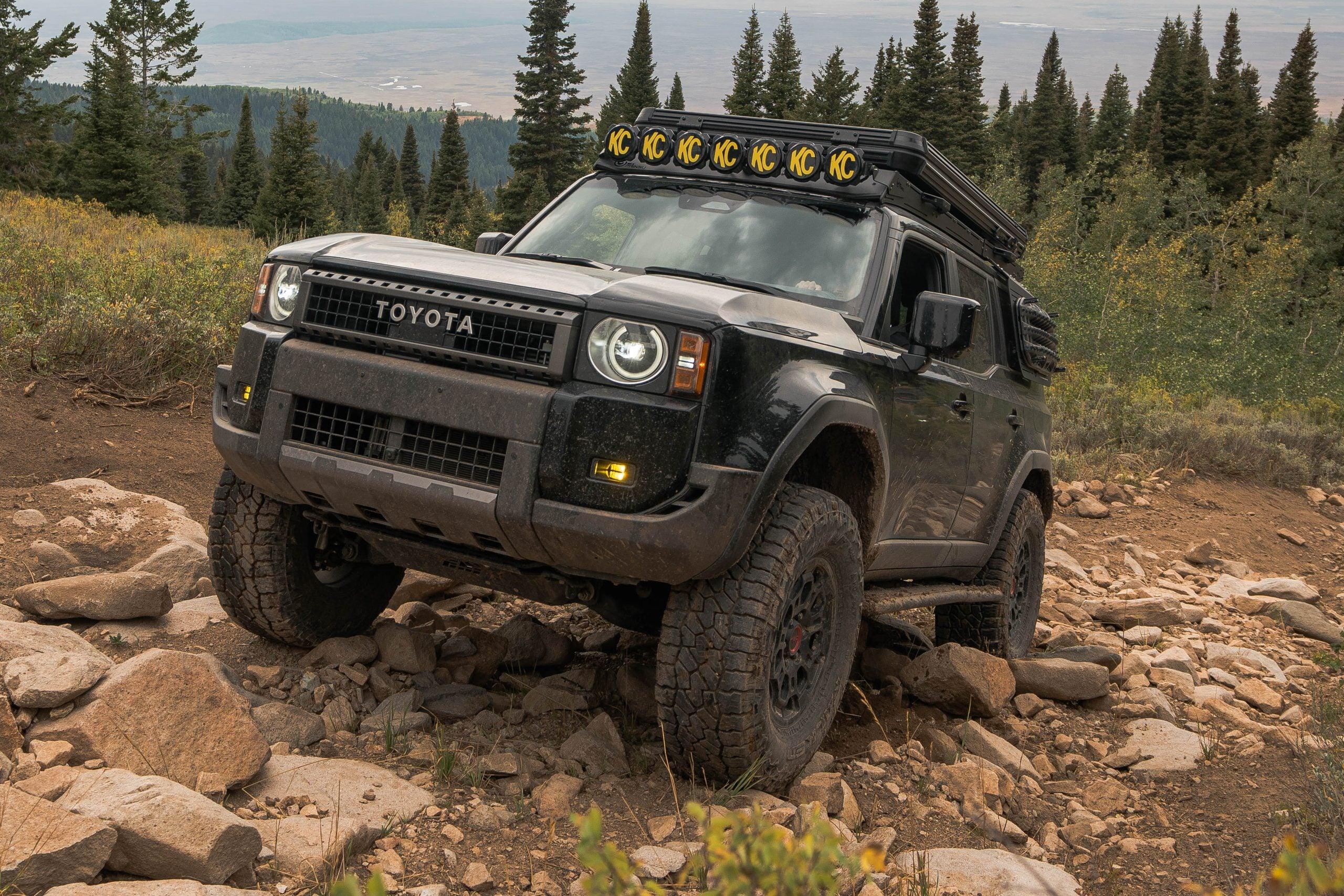 Toyota SUV with off-road accessories climbing rocky trail in a forested mountain area
