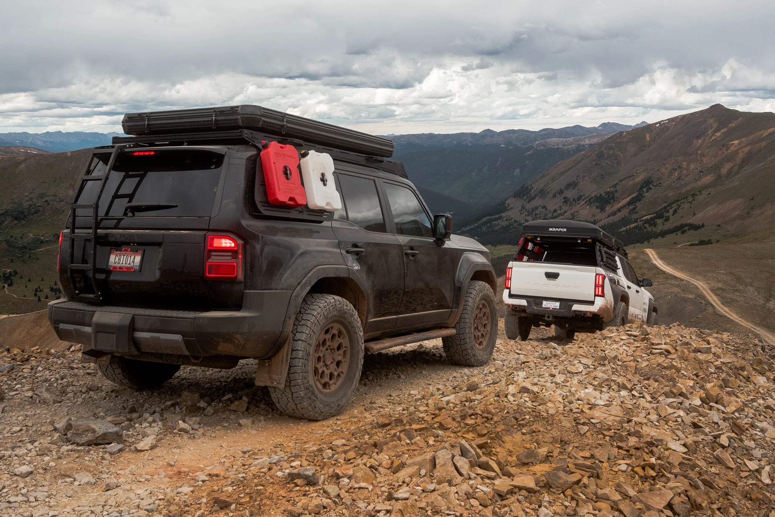 Toyota Land Cruiser and Tacoma with overlanding gear driving rocky mountain trail