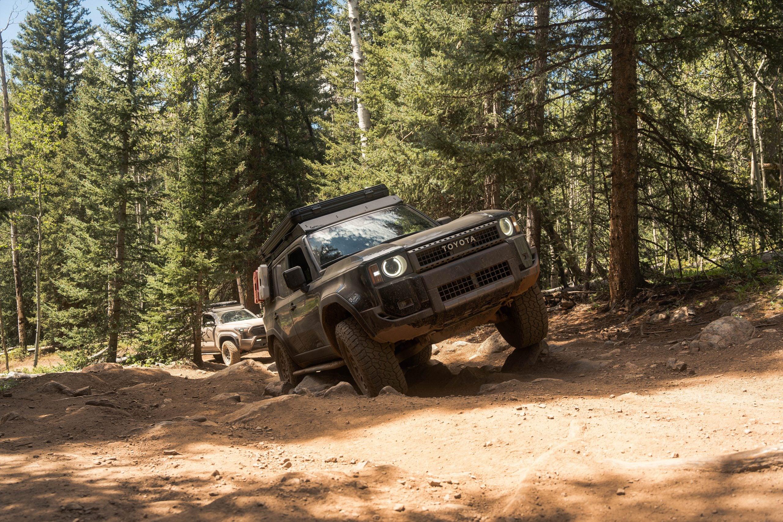 Toyota Land Cruiser off-roading on rocky forest trail with overlanding gear