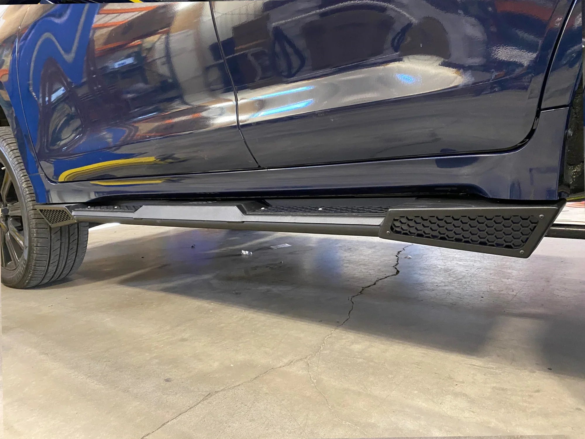 Lexus LX570 with off-road rock sliders installed, close-up side view in garage