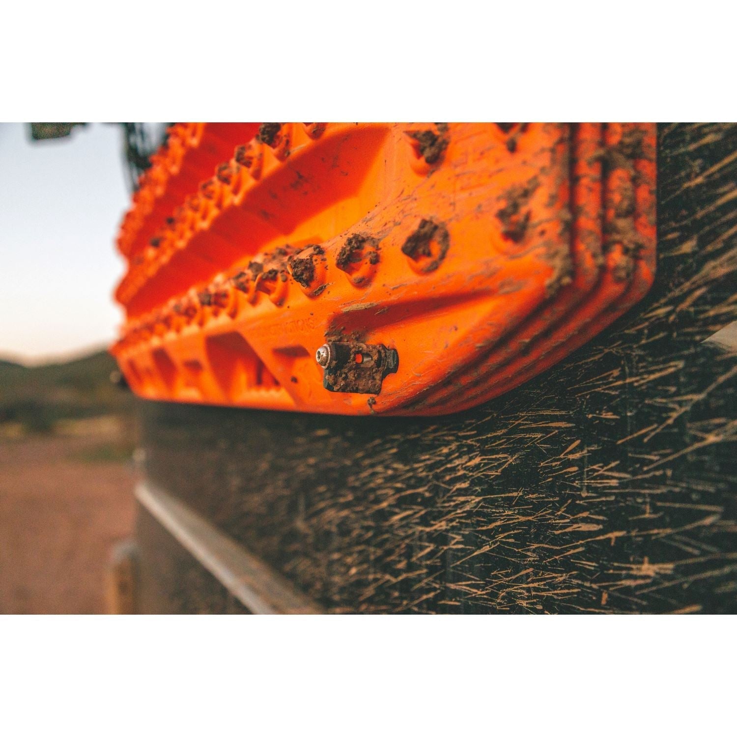Close-up of orange traction board mounted on vehicle with hardware, for overlanding