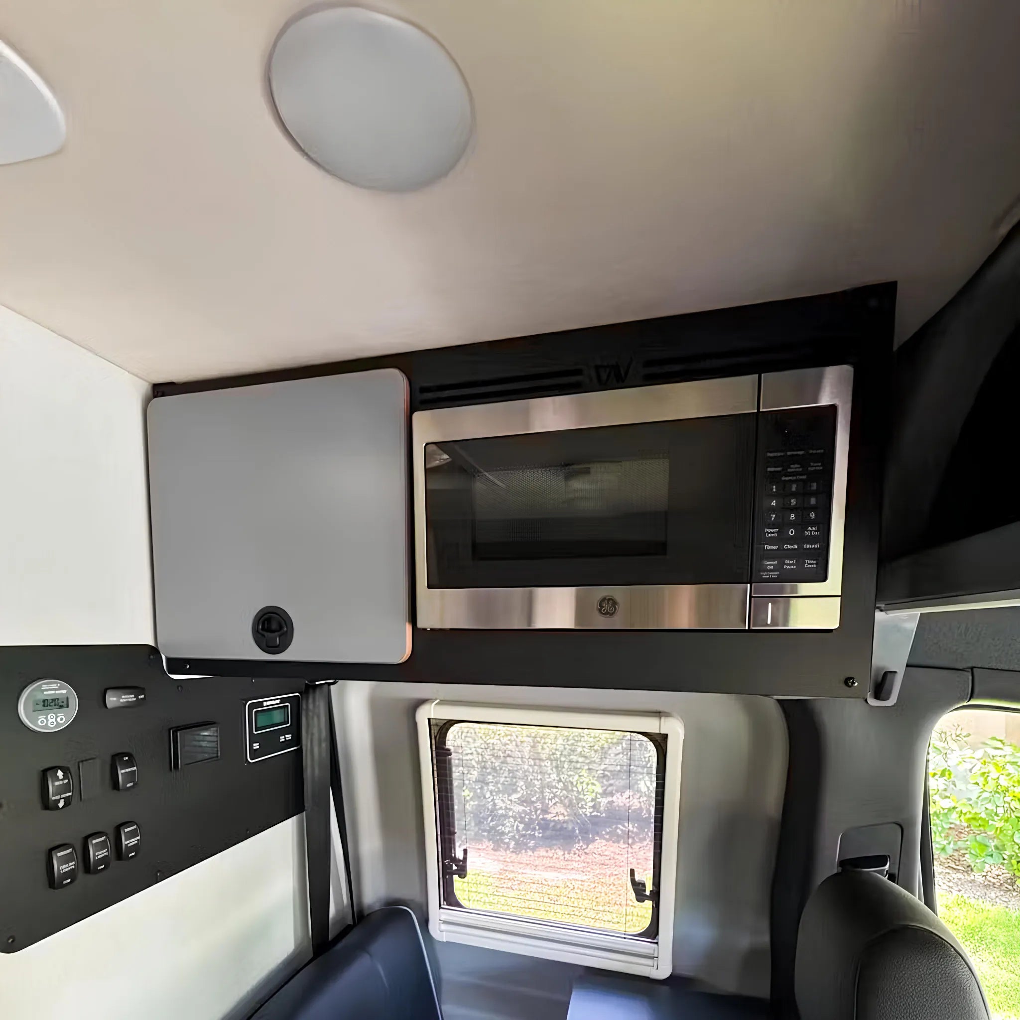 Overland camper van interior with microwave, control panel, storage cabinet, and window