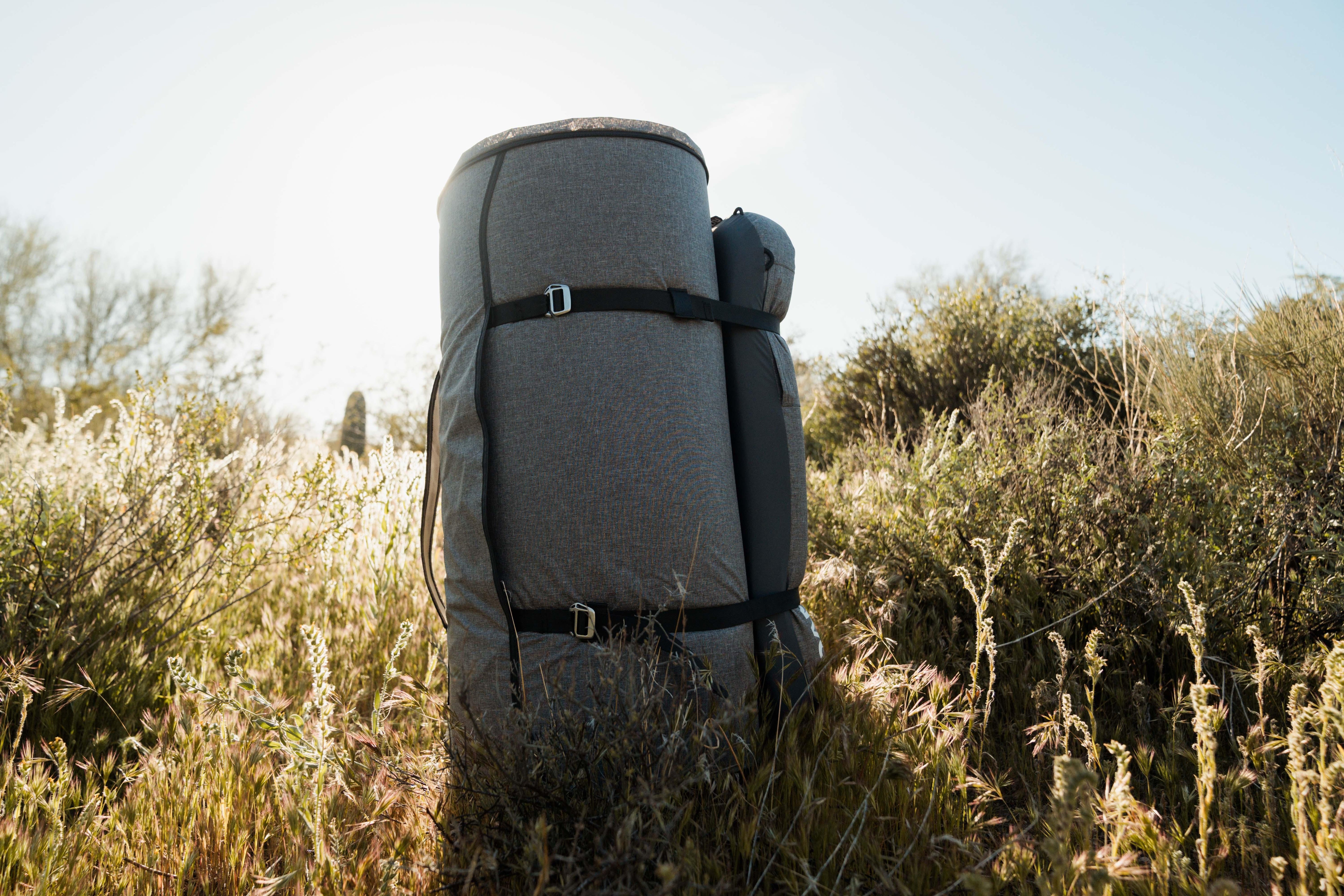 Rolled-up camping mattress with buckles outdoors in grassy wilderness, ideal for overlanding.