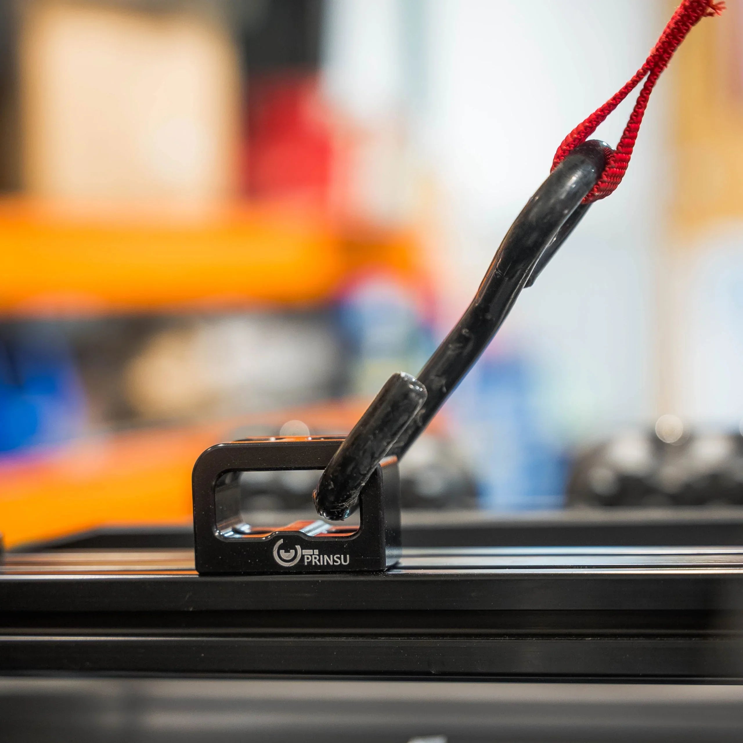 Heavy-duty multi-use anchor mounted on a roof rack with a hook and red strap