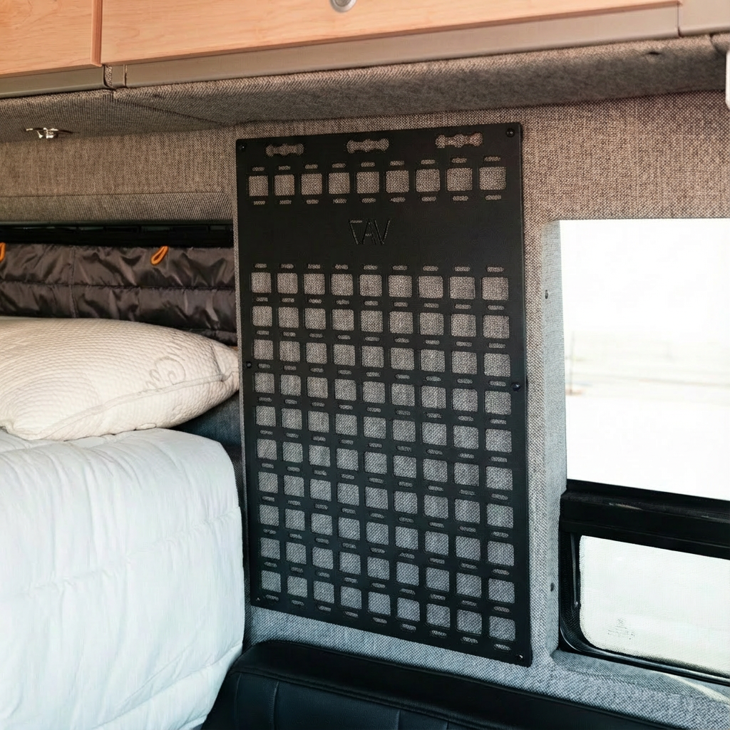 Modular vehicle storage panel mounted inside camper with bed and storage cabinets visible