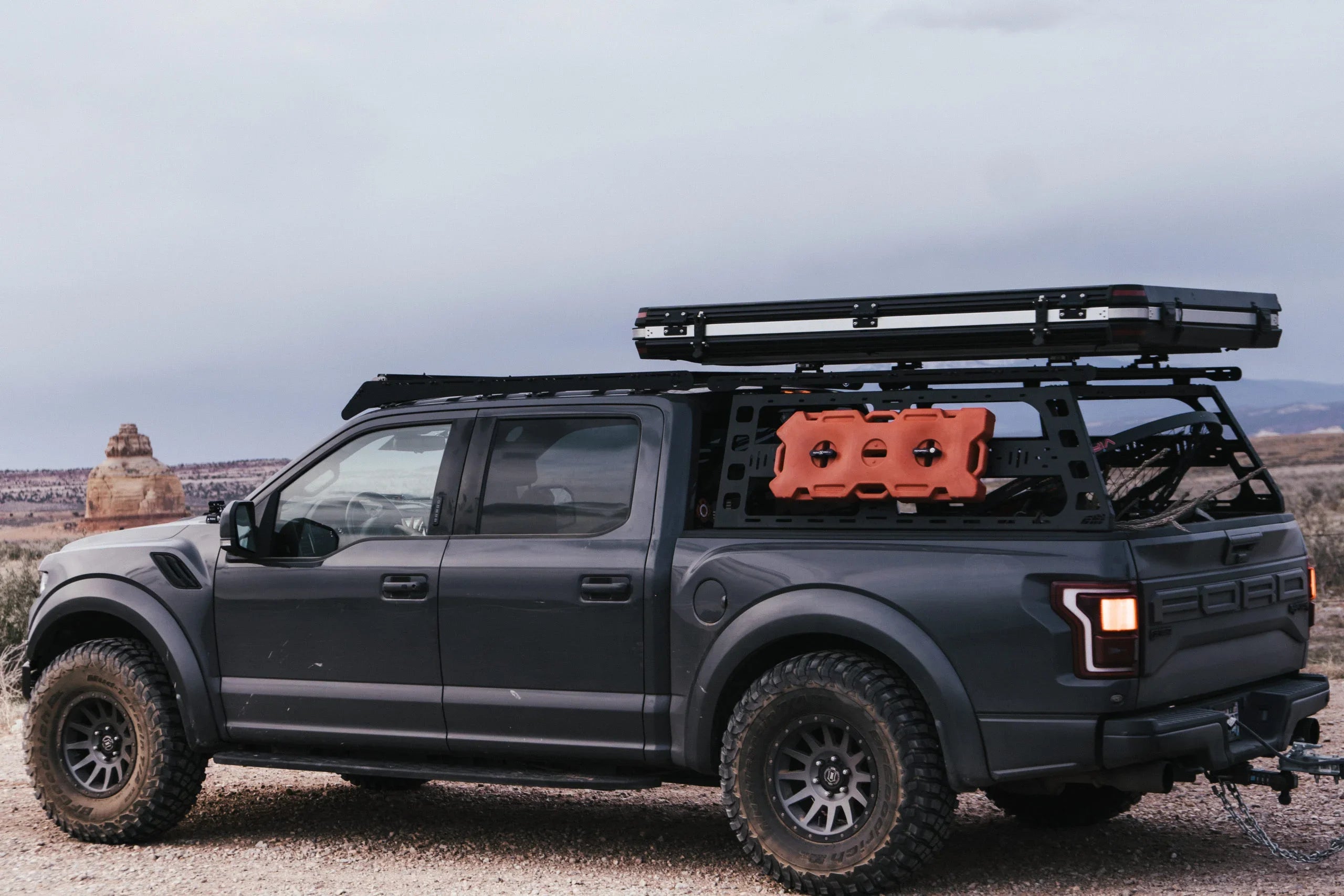 Ford Raptor truck with offroad bedrack, camping gear, and recovery boards in desert