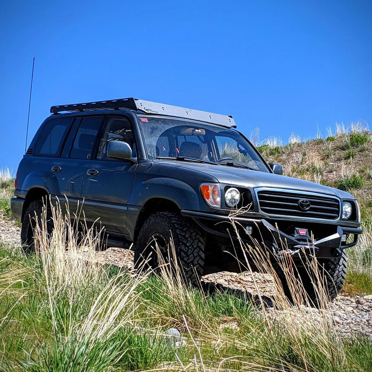Toyota Land Cruiser 100 Series with roof rack off-road on grassy rocky trail
