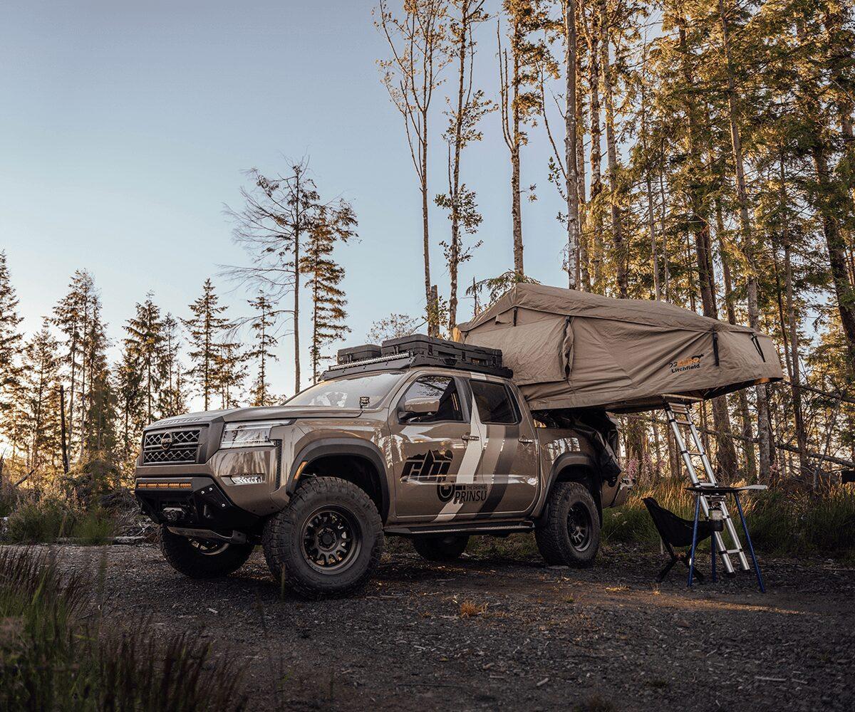 Overland Nissan Frontier with Prinsu roof rack and rooftop tent parked in forest campsite