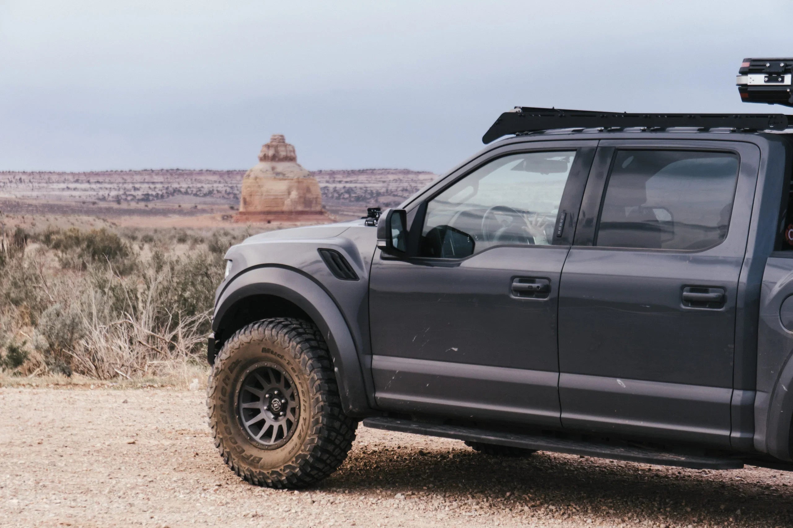 Ford Raptor with Prinsu roof rack parked outdoors in a desert landscape