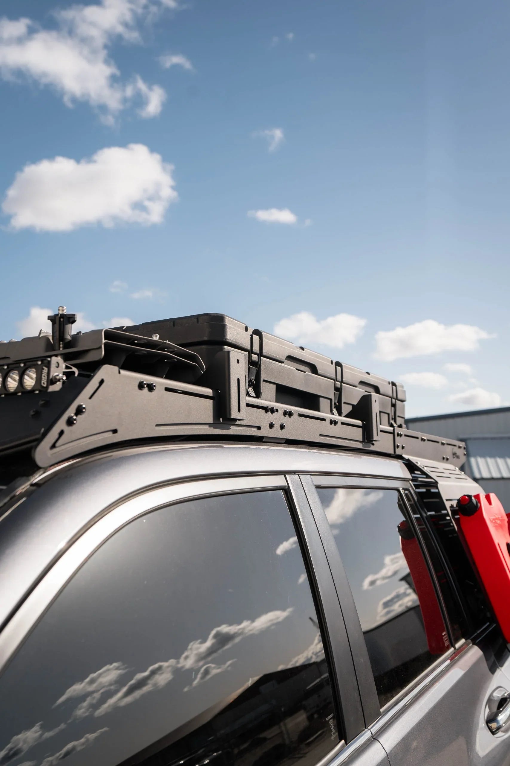 Overland vehicle roof rack with pro awning mounts and gear case under blue sky