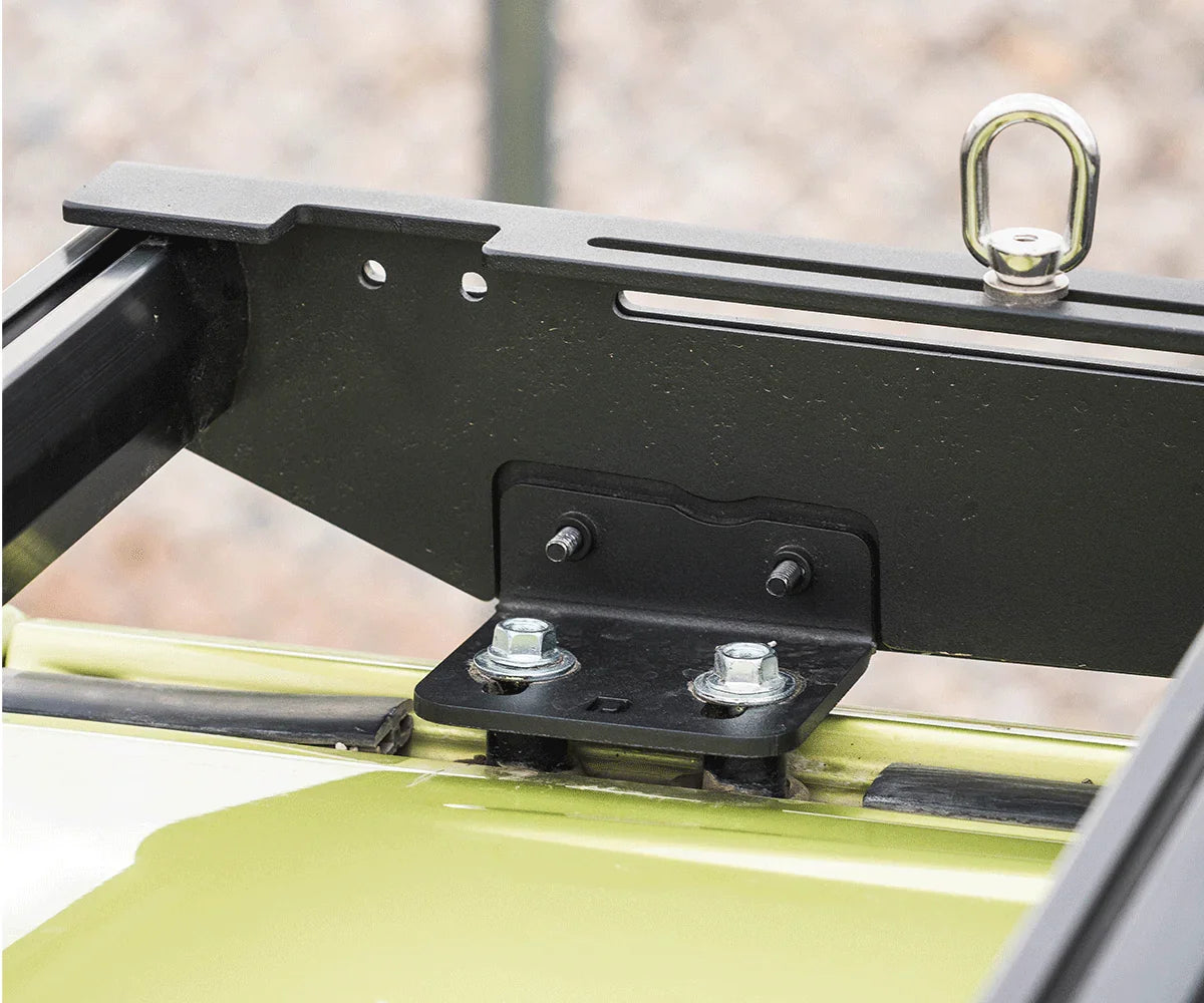 Black metal roof rack mounting bracket with bolts installed on a green vehicle roof