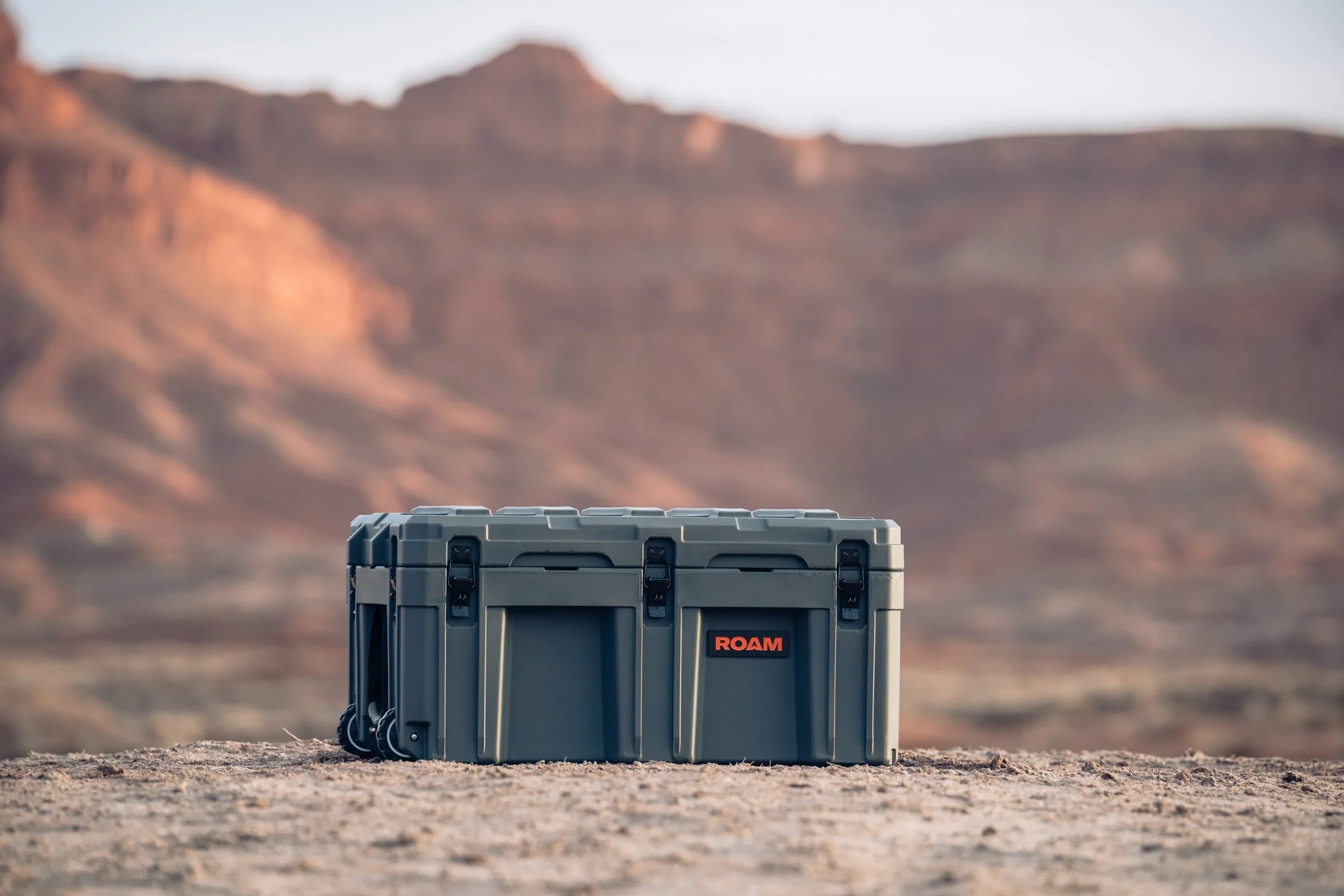 Heavy-duty overland storage case with latches on desert terrain, rugged adventure gear