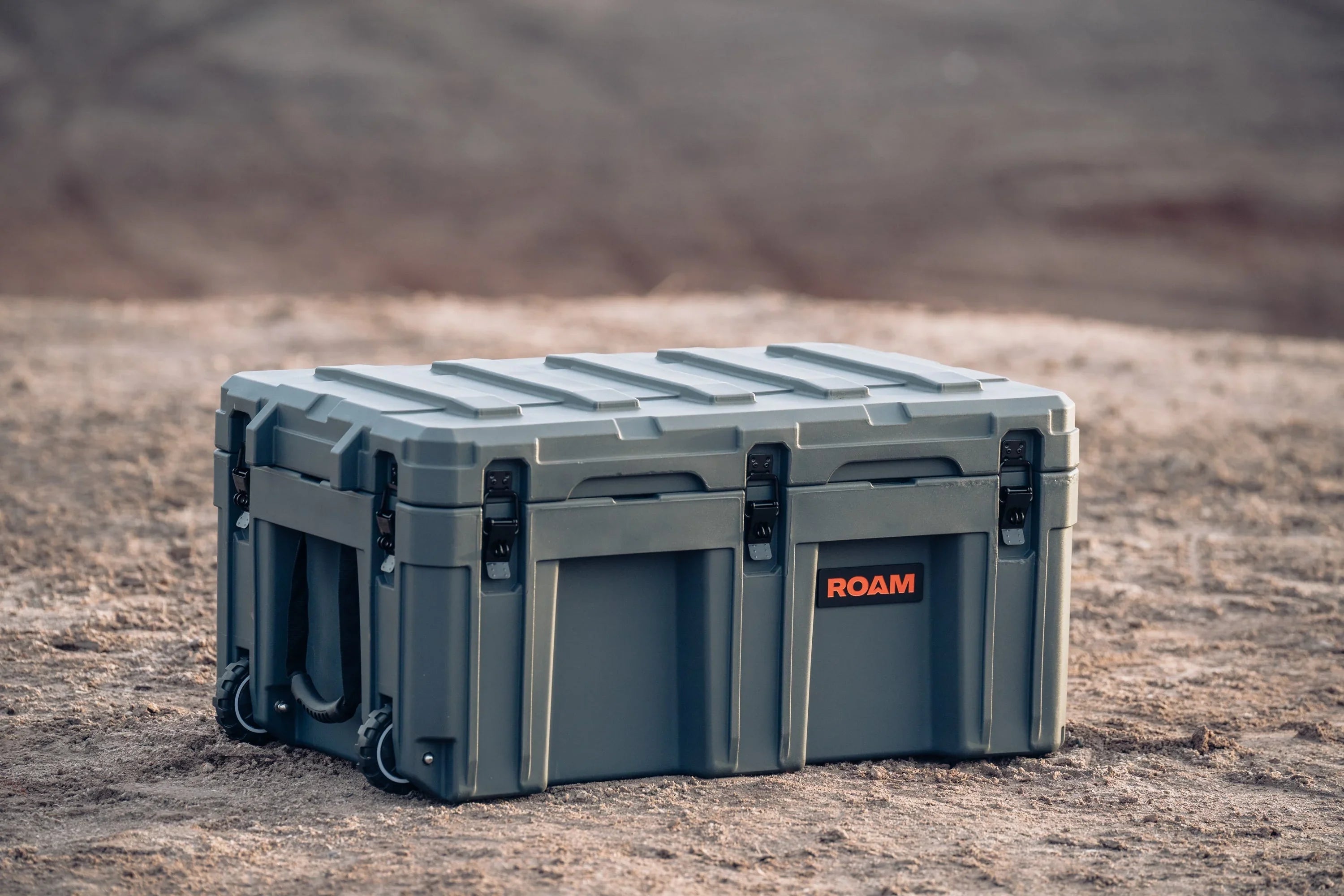 Heavy-duty gray overlanding storage case with ROAM logo, positioned on rugged outdoor terrain.
