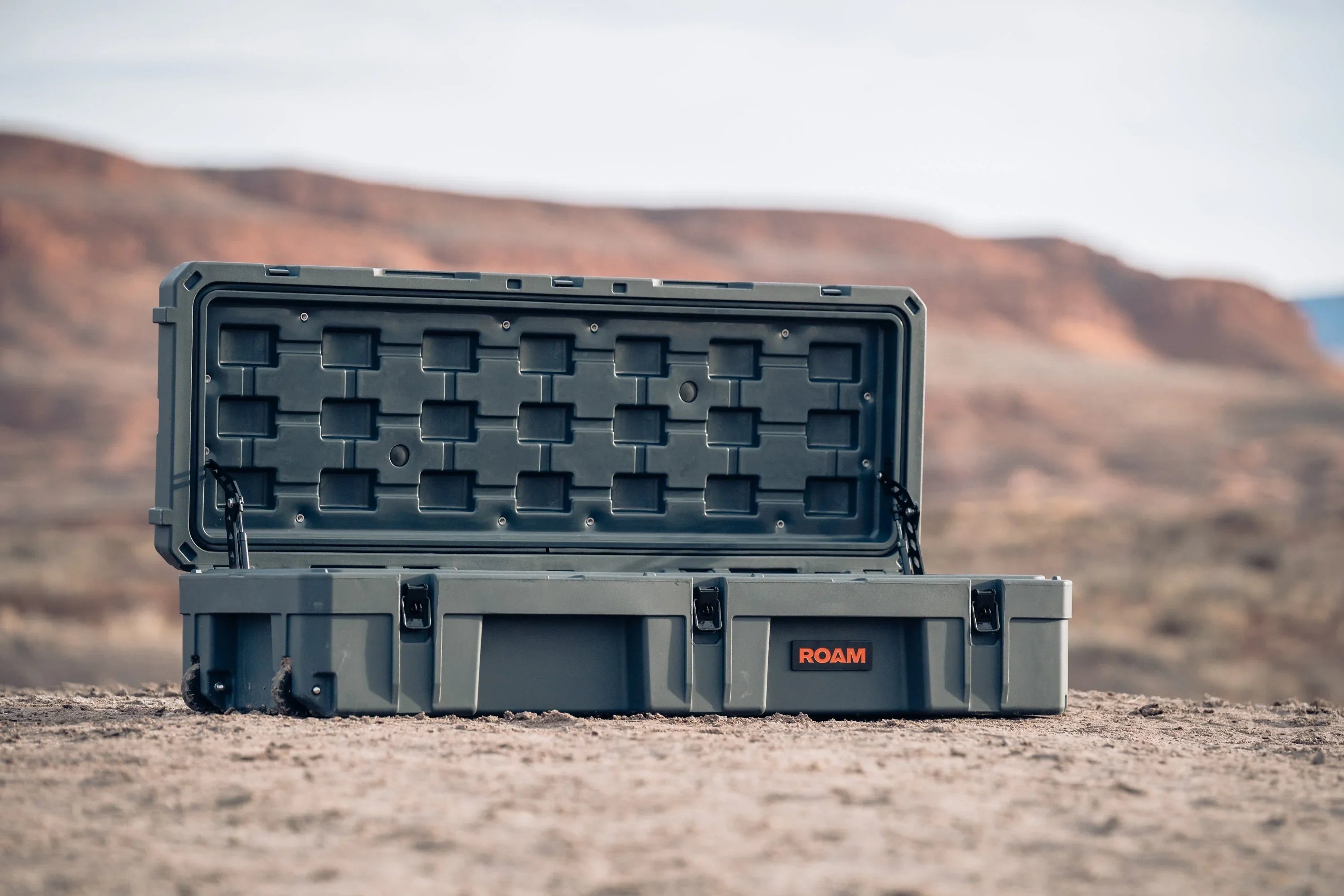 Heavy-duty ROAM storage case open on desert ground, ideal for overlanding gear organization