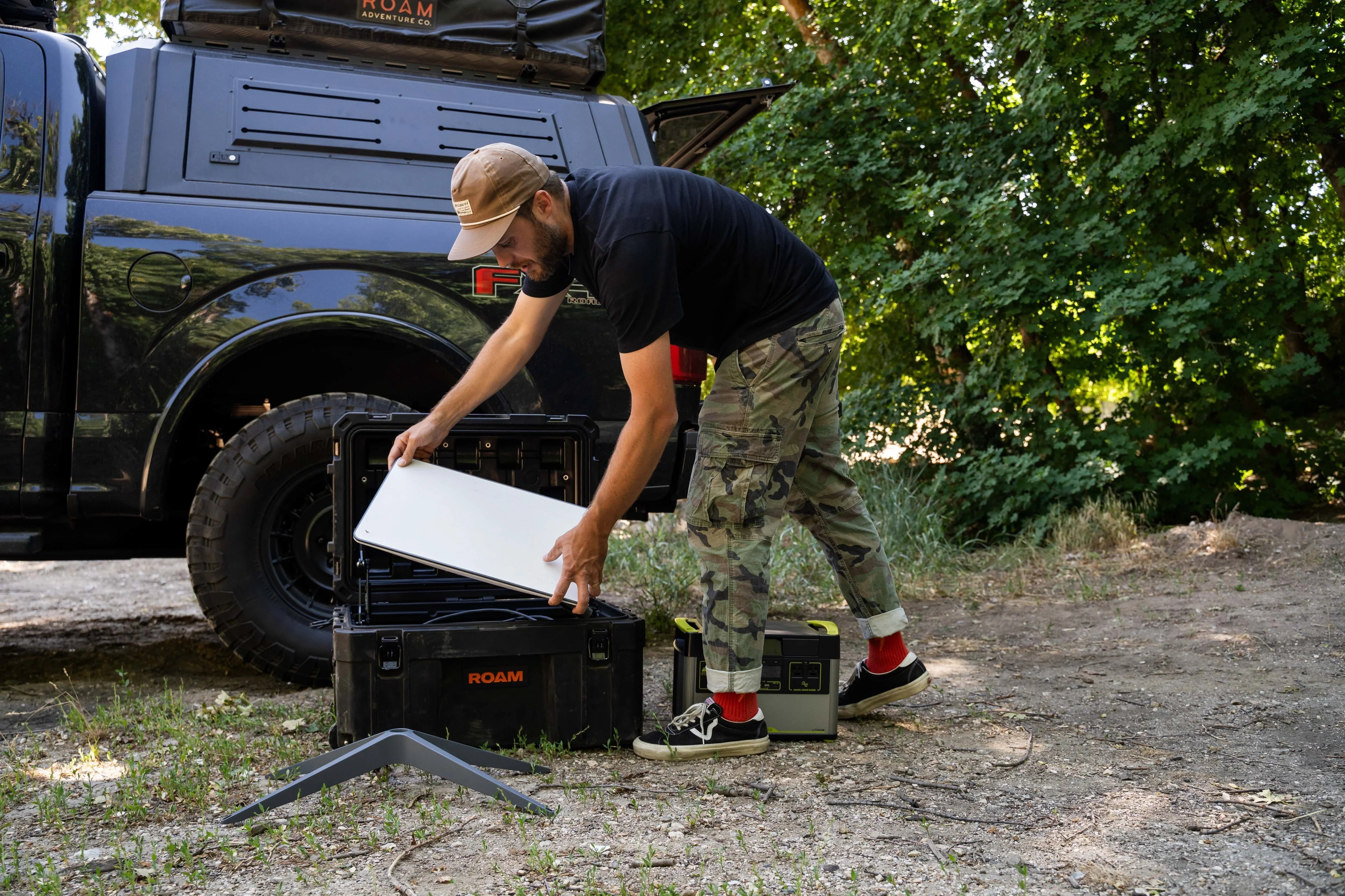 Man setting up outdoor camping gear next to truck with overlanding storage case
