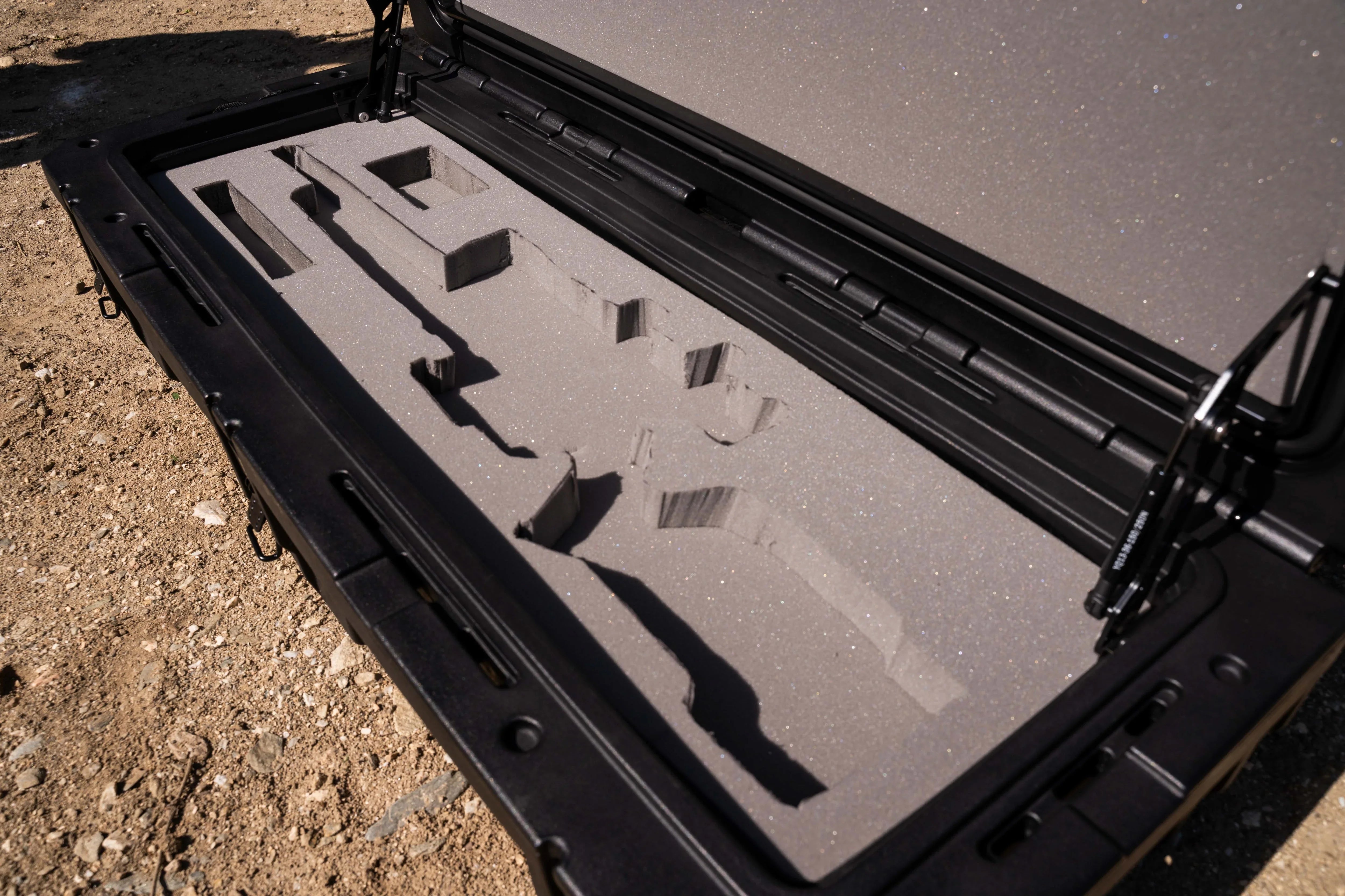Open hard case with custom foam inserts for overlanding or expedition gear on dirt ground