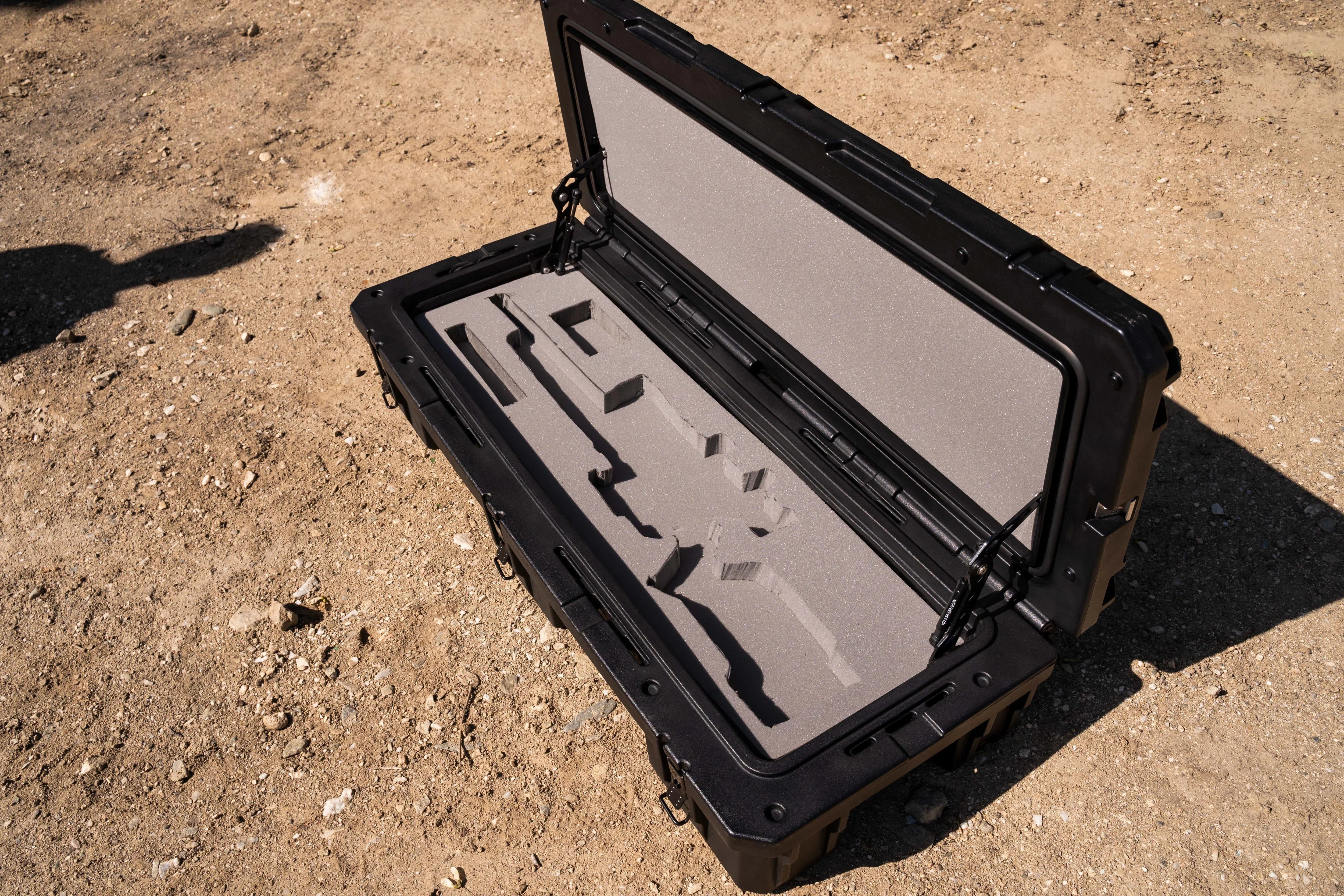 Durable black hard case with custom foam insert for gear storage, outdoors on dirt