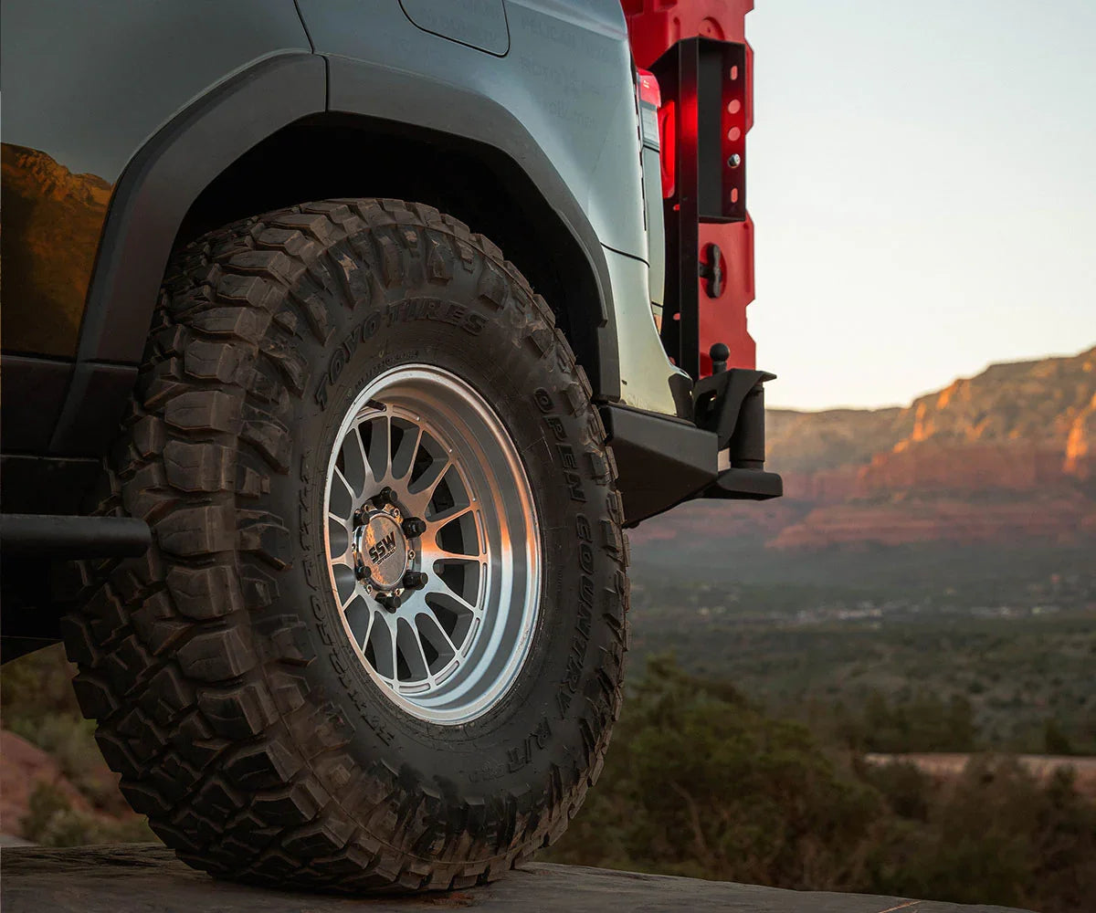 Off-road tire and wheel on overland vehicle with mountain landscape background