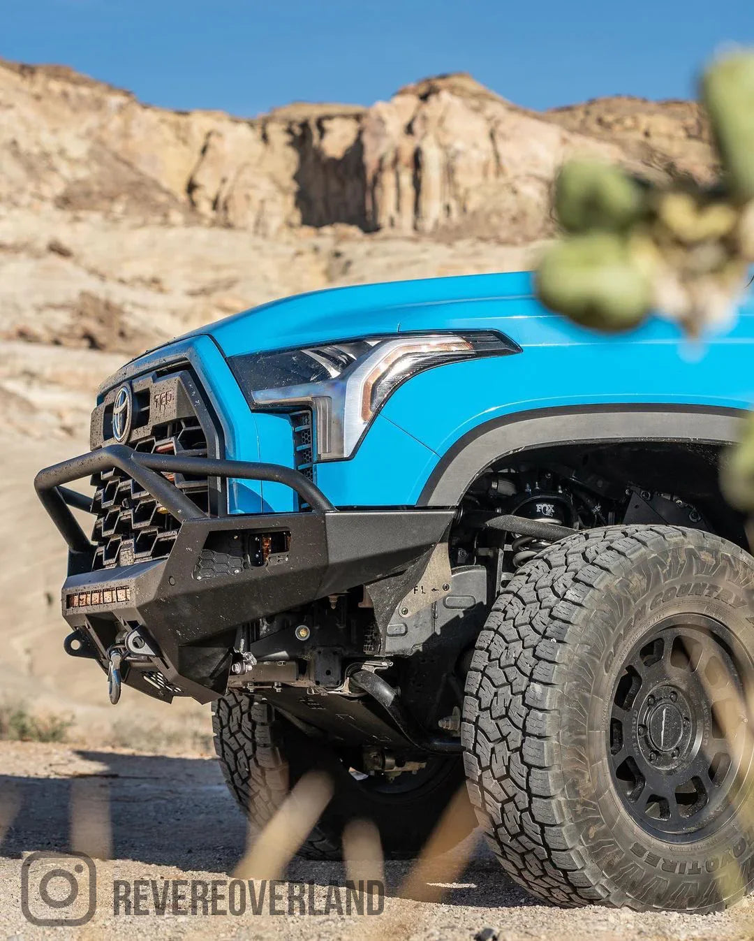 Blue Toyota Tundra with CBI off-road front bumper and rugged tires in a desert landscape