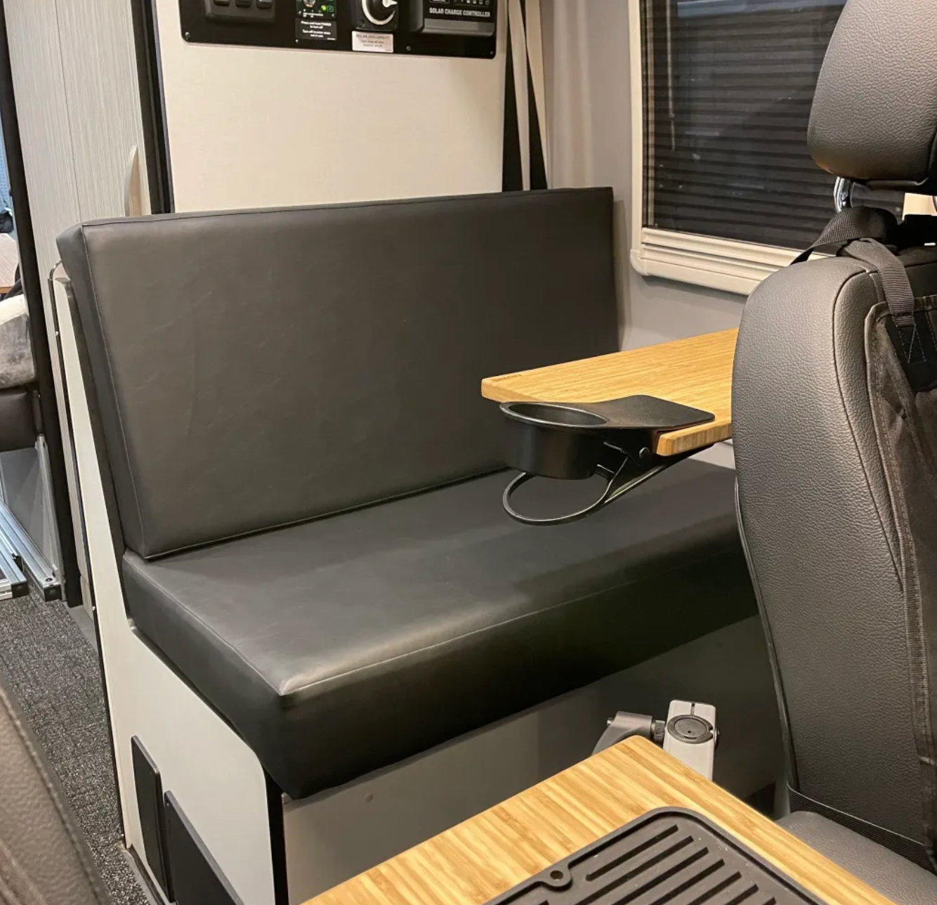Overland vehicle interior with black bench seat and wood camping table