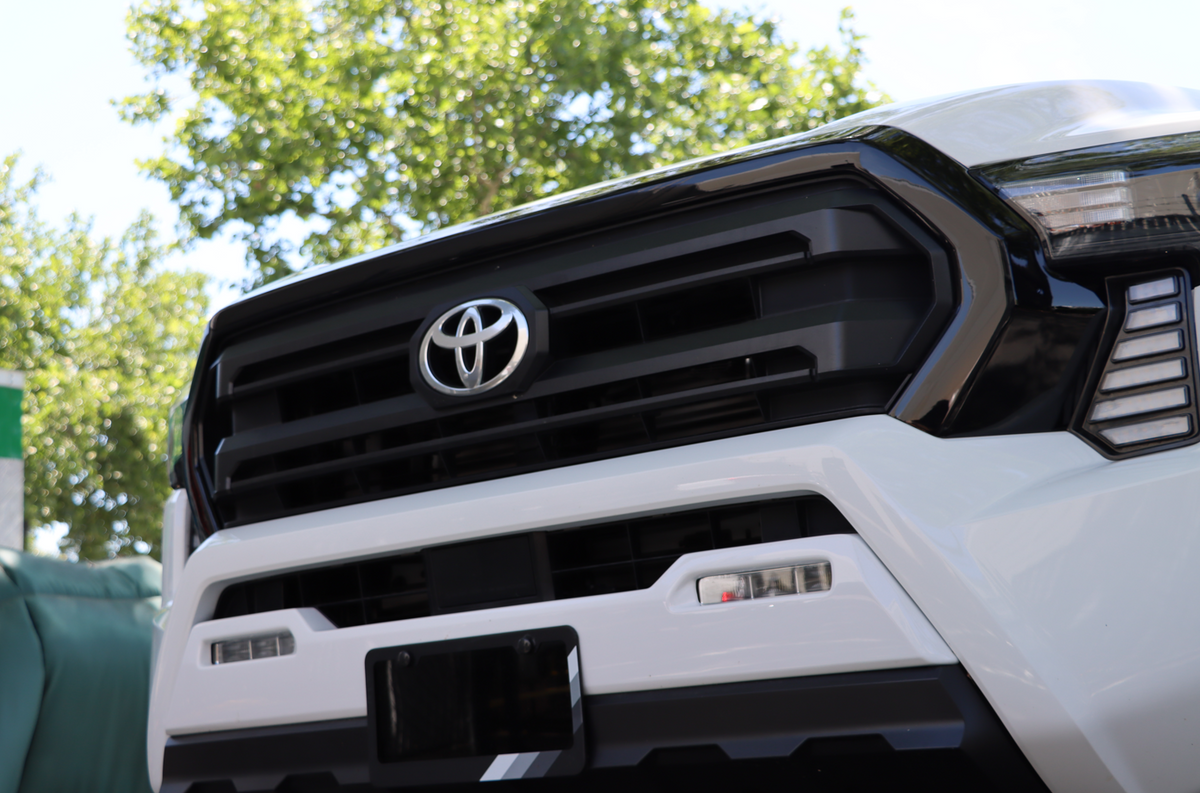 White 2024-2026 Toyota Tacoma front end with the Ecoological black grille overlay installed around the Toyota emblem