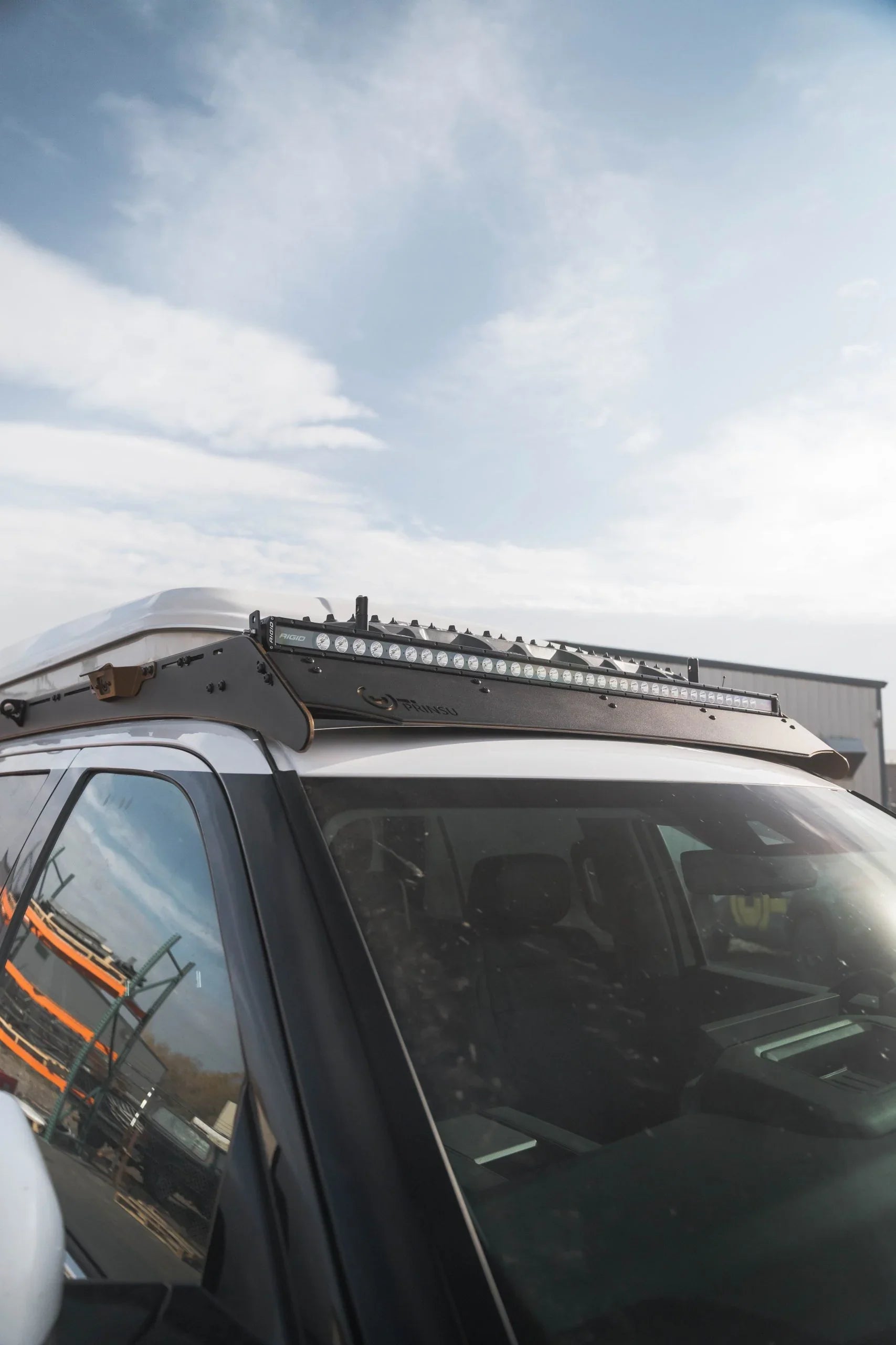 Close-up of a vehicle roof rack with mounted LED light bar for overlanding