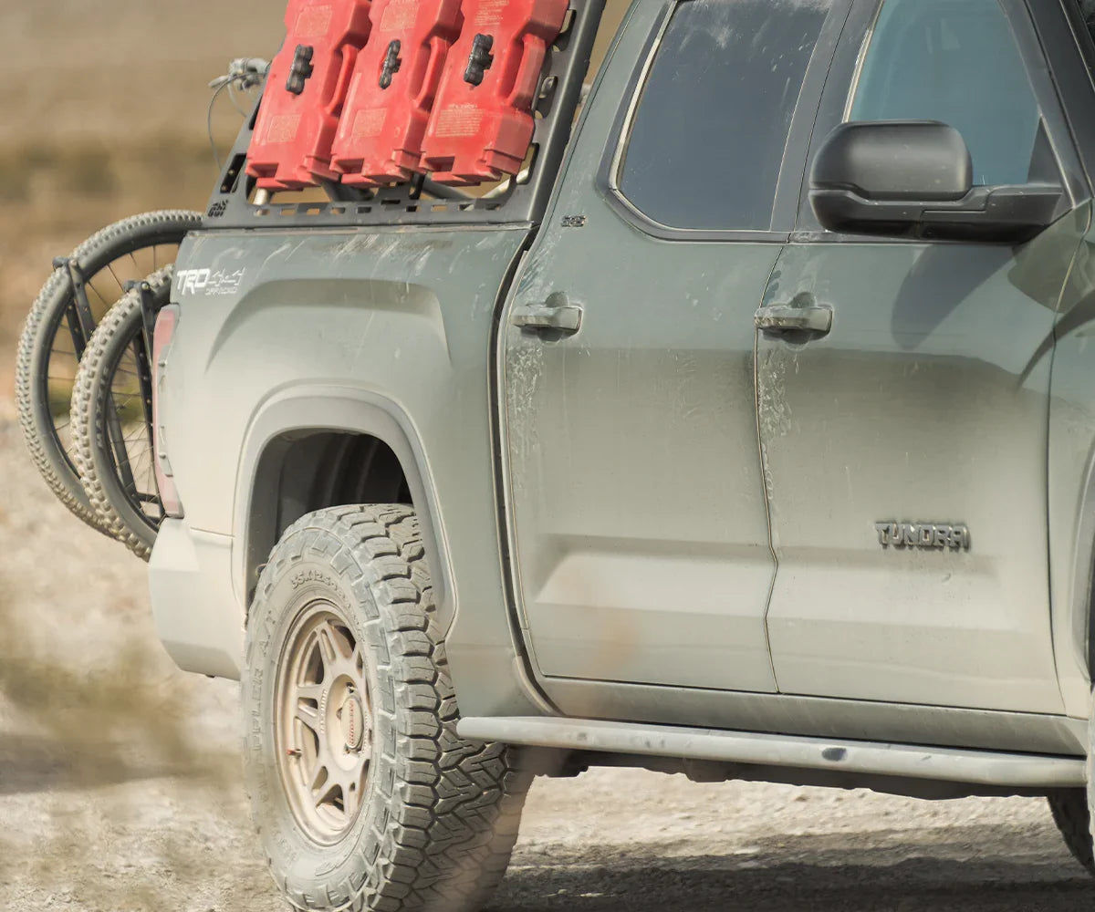 Side view of Toyota Tundra with rock sliders, off-road gear, and spare bicycle tire
