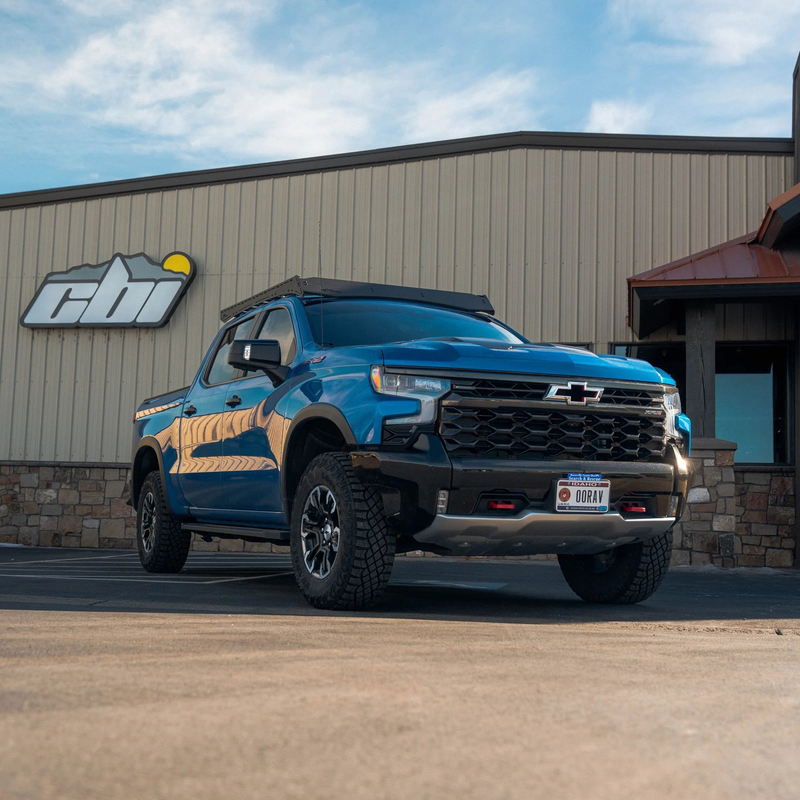 Blue Chevrolet Silverado ZR2 with roof rack parked in front of CBI building, overland truck accessories